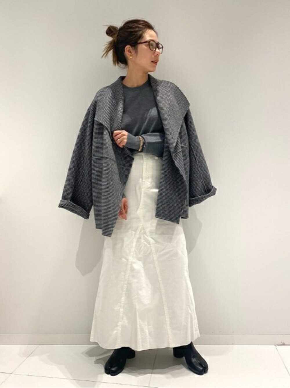 グレー系のニット/セーター、ホワイト系のスカート、ブラック系のその他アウターを着用したレディースの冬コーディネートの1枚目の写真