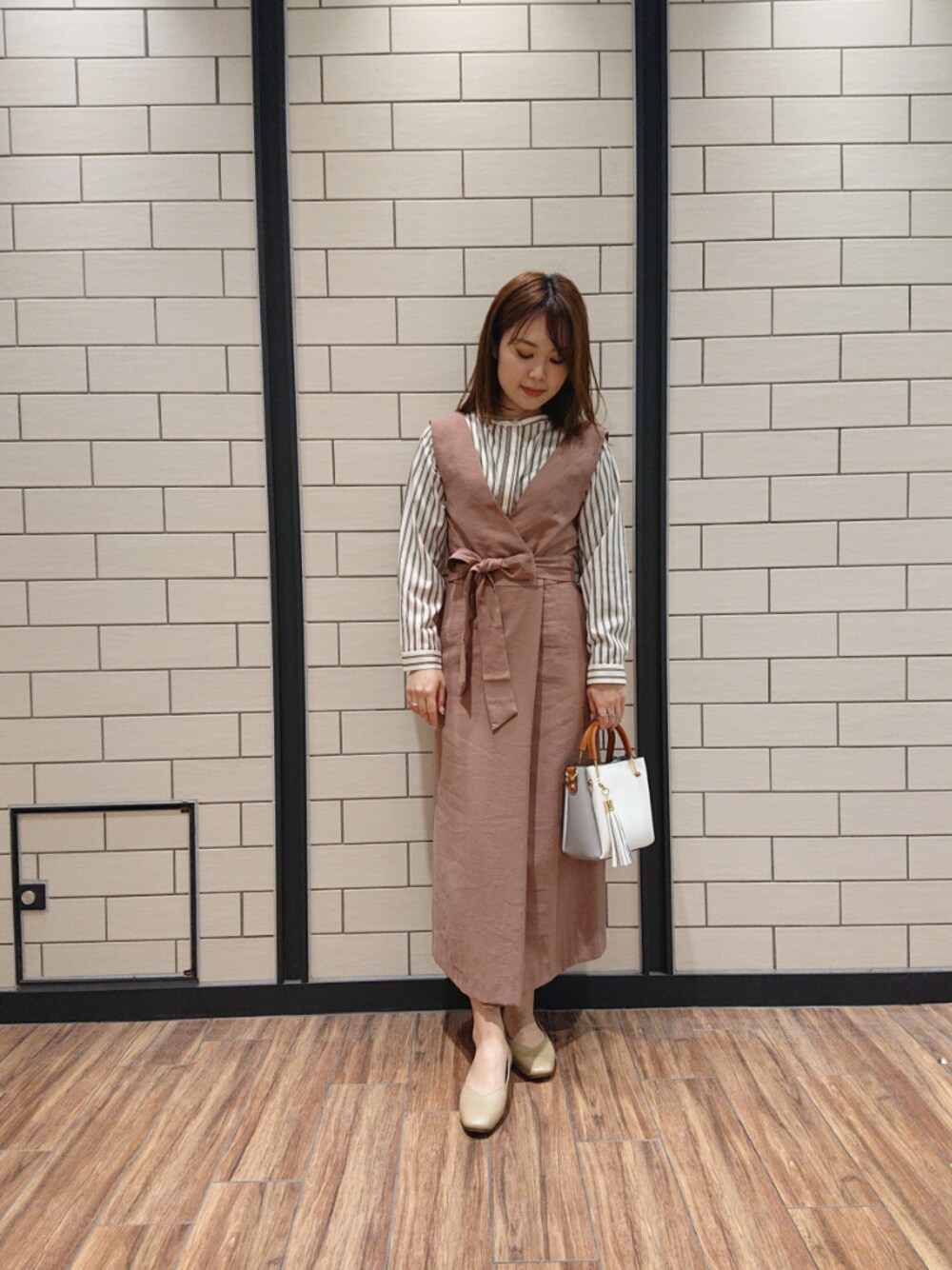 ベージュ系のワンピース、ホワイト系のトートバッグ、ベージュ系のパンプスを着用したレディースの春コーディネートの1枚目の写真