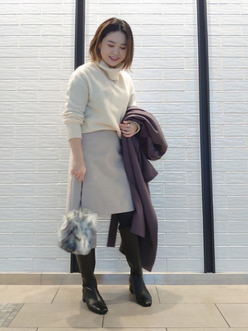 ホワイト系のニット/セーター、グレー系のその他アウター、ブラック系のブーツを着用したレディースの冬コーディネートの1枚目の写真