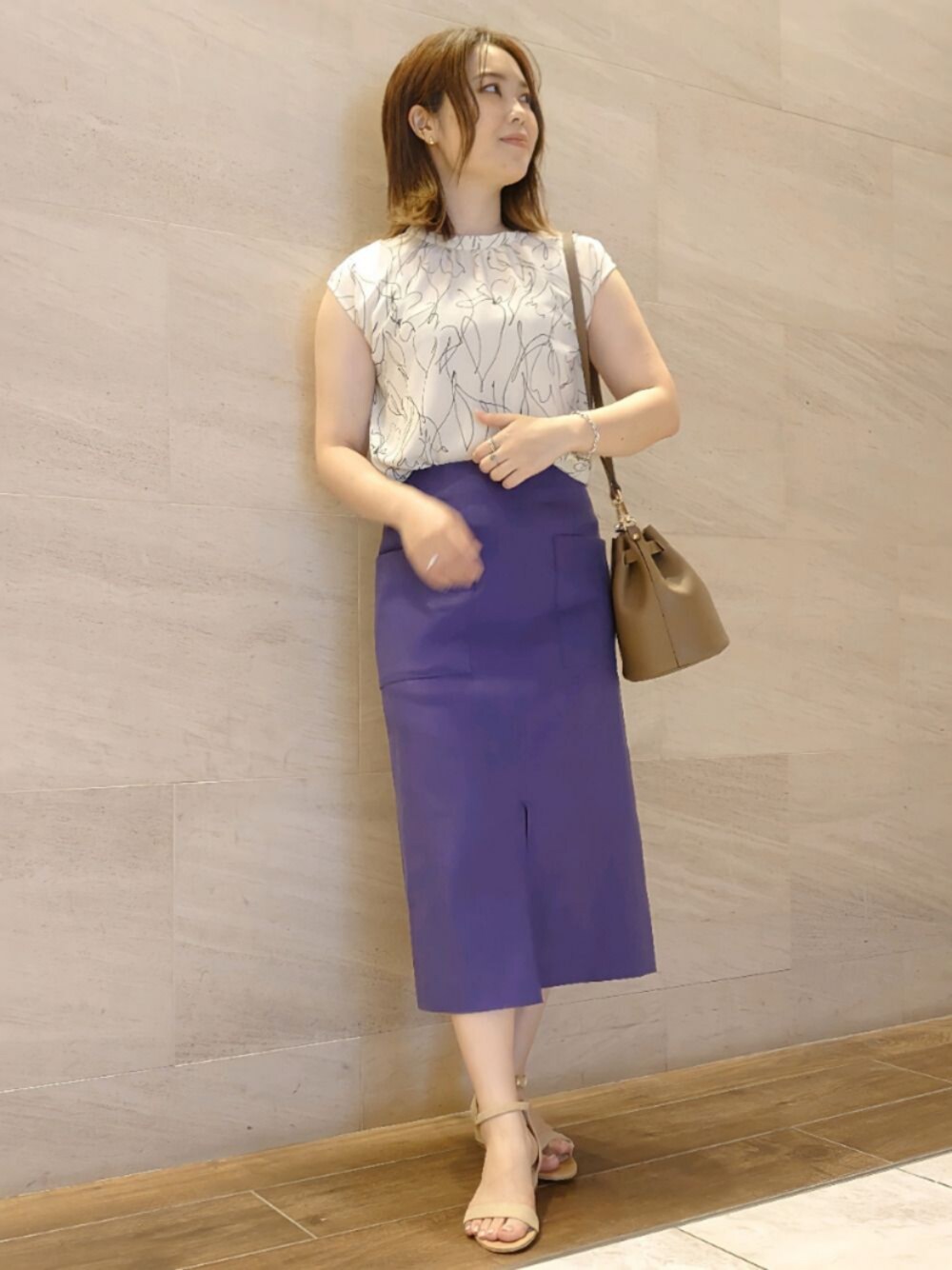 ブルー系のスカート、ベージュ系のショルダーバッグ、ベージュ系のサンダルを着用したレディースの春コーディネートの1枚目の写真