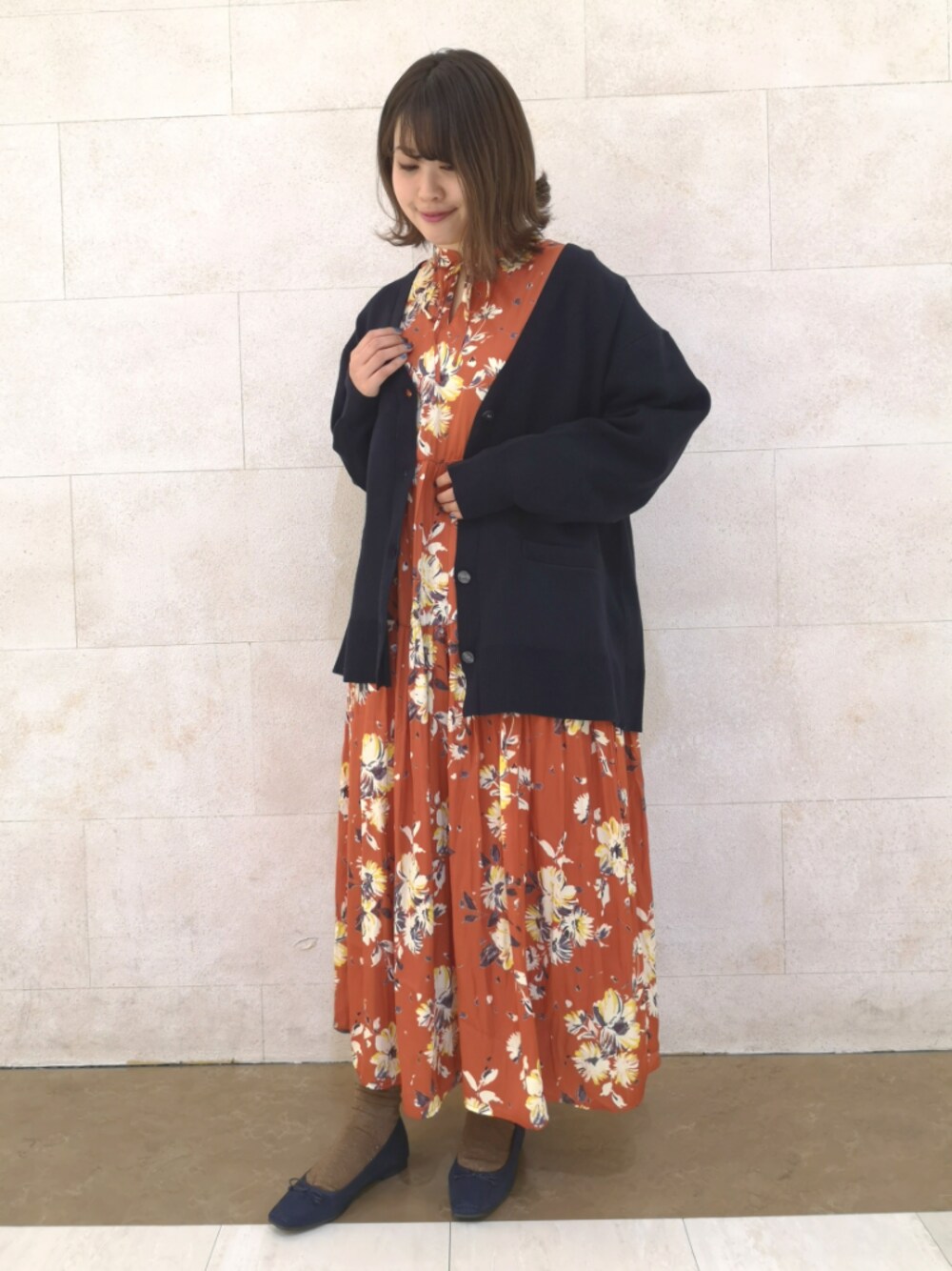 レッド系のワンピース、ブルー系のカーディガン/ボレロ、ブラック系のシューズを着用したレディースの冬コーディネートの1枚目の写真