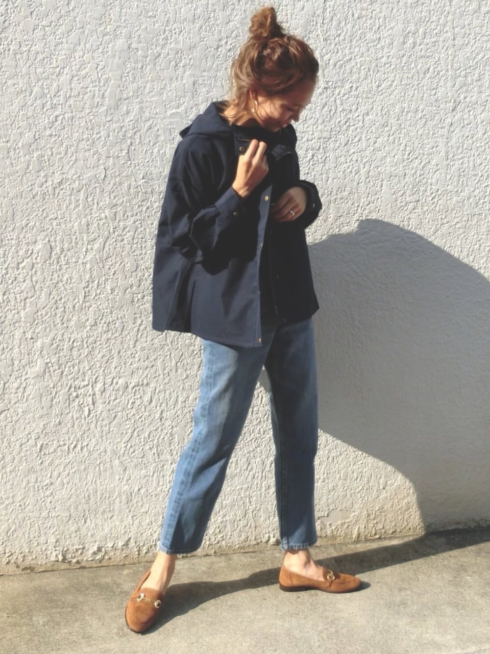 ブルー系のデニムパンツ、ブラウン系のローファー、ブルー系のマウンテンパーカーを着用したレディースの秋コーディネートの1枚目の写真