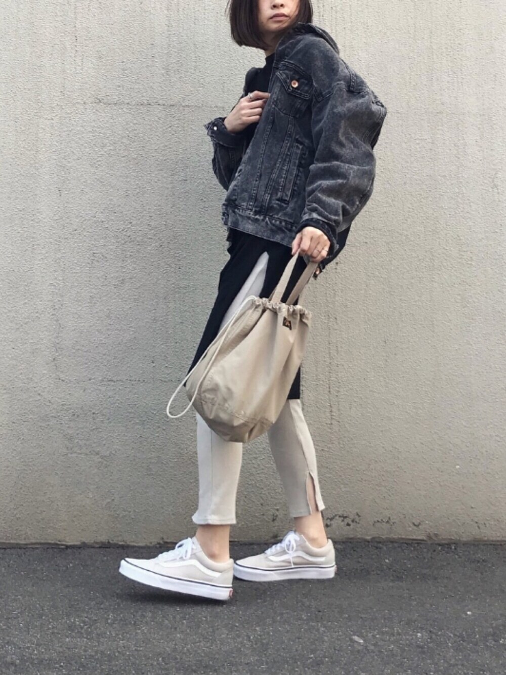 グレー系のデニムジャケット、ブラック系のワンピース、ベージュ系のスニーカーを着用したレディースの春コーディネートの1枚目の写真