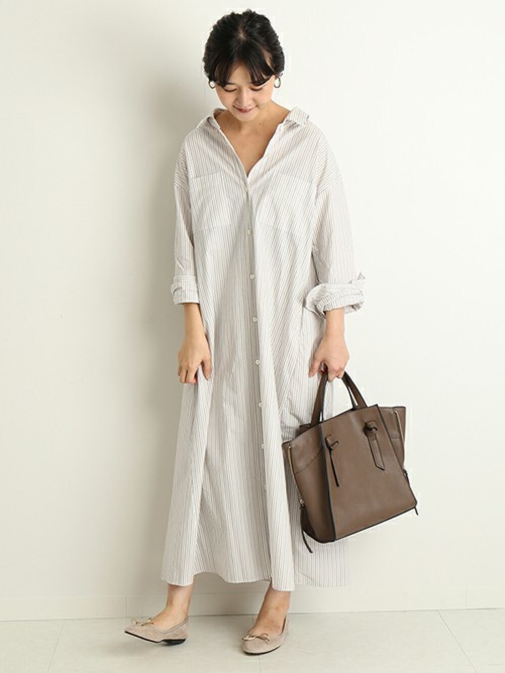 ベージュ系のシャツワンピース、グレー系のバレエシューズ、ベージュ系のハンドバッグを着用したレディースの秋コーディネートの1枚目の写真