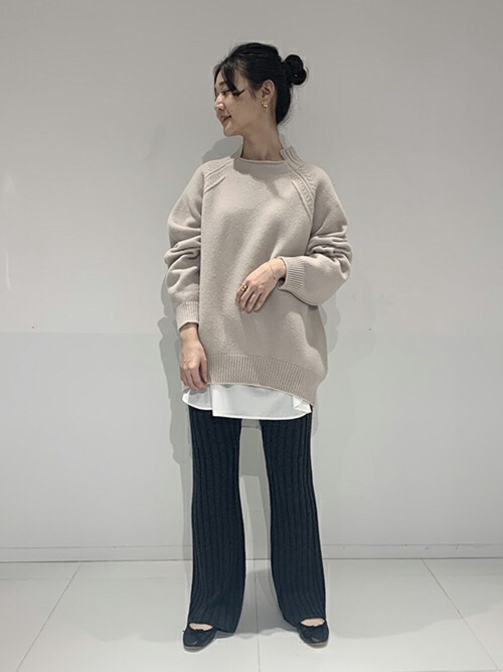 ベージュ系のニット/セーター、ホワイト系のシャツ/ブラウス、ブラック系のバレエシューズを着用したレディースの冬コーディネートの1枚目の写真