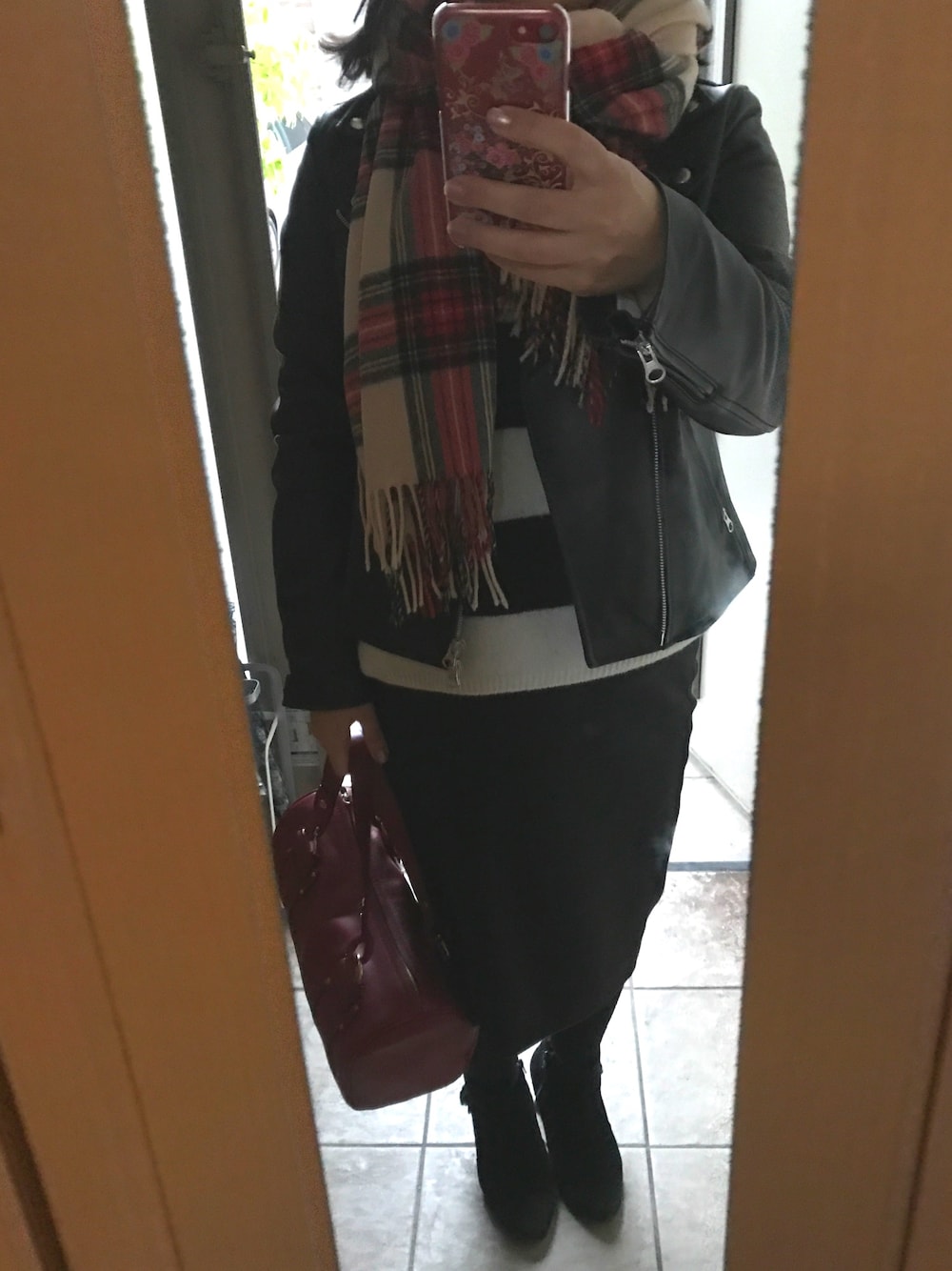 ブラック系のライダースジャケット、ホワイト系のニット/セーター、ブラック系のスカートを着用したレディースの秋コーディネートの1枚目の写真