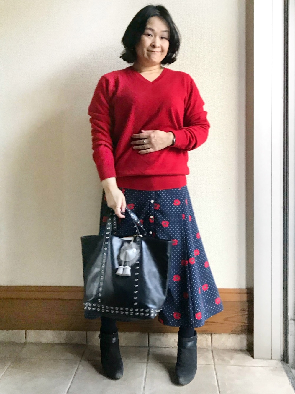 レッド系のニット/セーター、ブルー系のスカート、ブルー系のトートバッグを着用したレディースの冬コーディネートの1枚目の写真