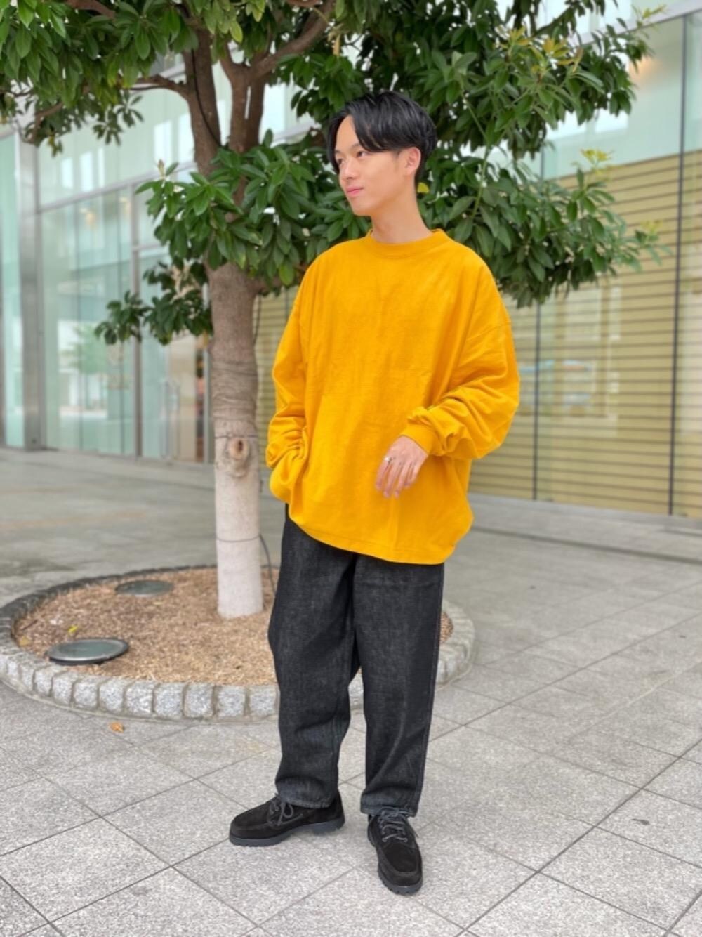 ブラック系のデニムパンツ、ブラック系のモカシン/デッキシューズ、イエロー系のTシャツ/カットソーを着用したメンズの秋コーディネートの1枚目の写真