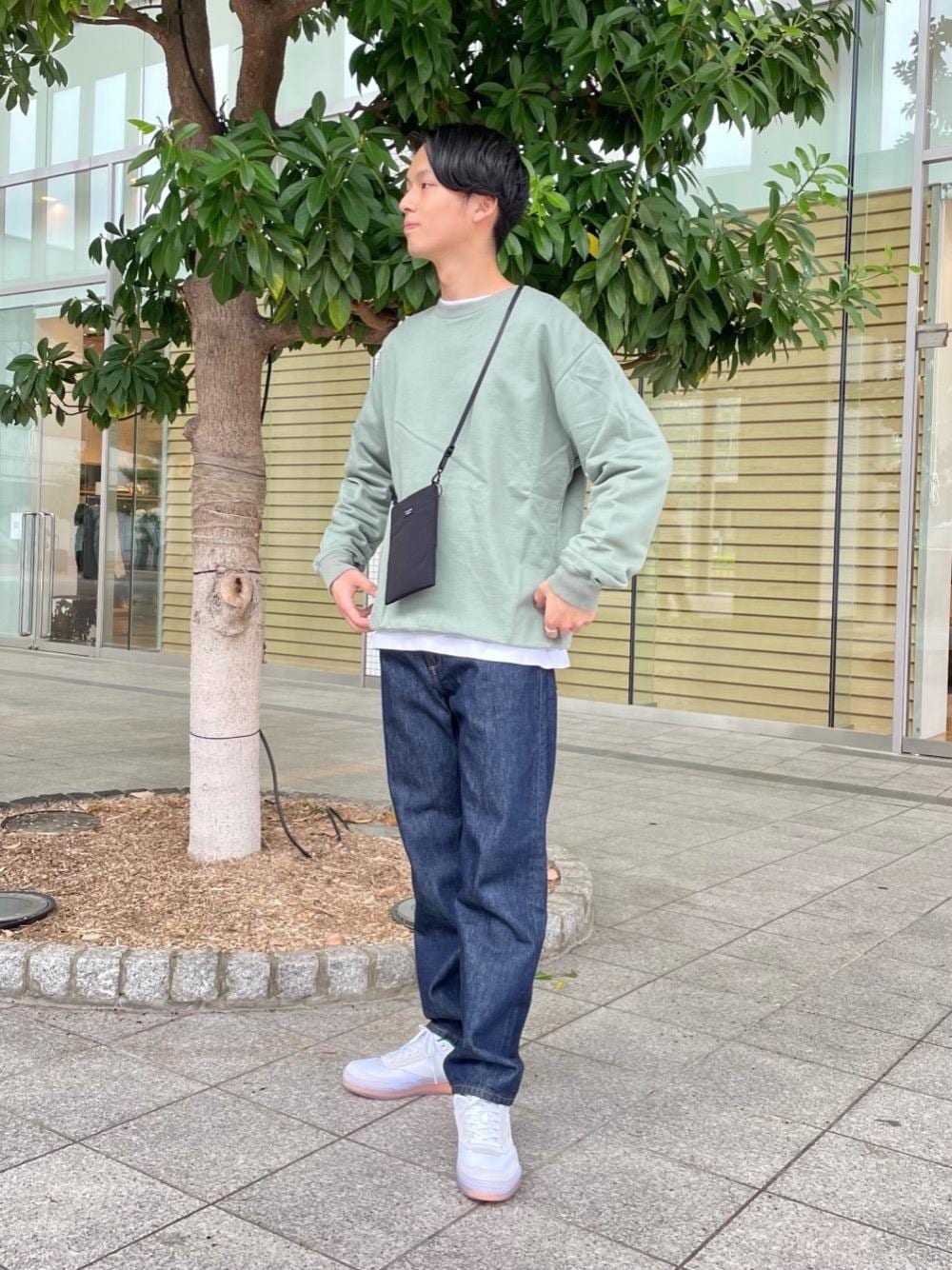 グリーン系のスウェット、ブルー系のデニムパンツ、ブラック系のショルダーバッグを着用したメンズの秋コーディネートの1枚目の写真