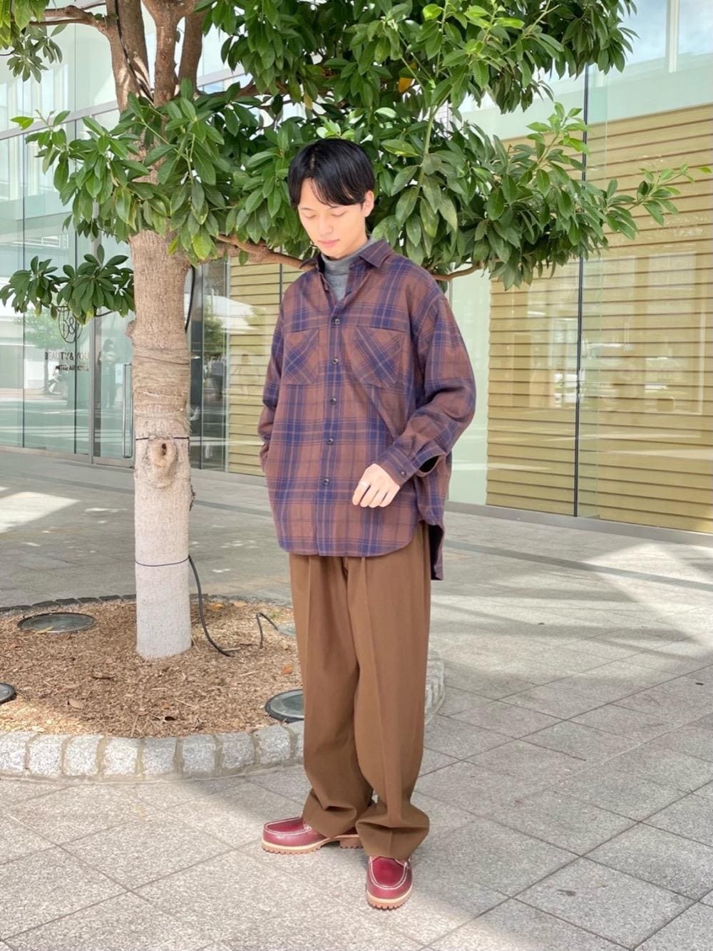 レッド系のモカシン/デッキシューズ、ブラウン系のシャツ/ブラウス、グレー系のニット/セーターを着用したメンズの秋コーディネートの1枚目の写真