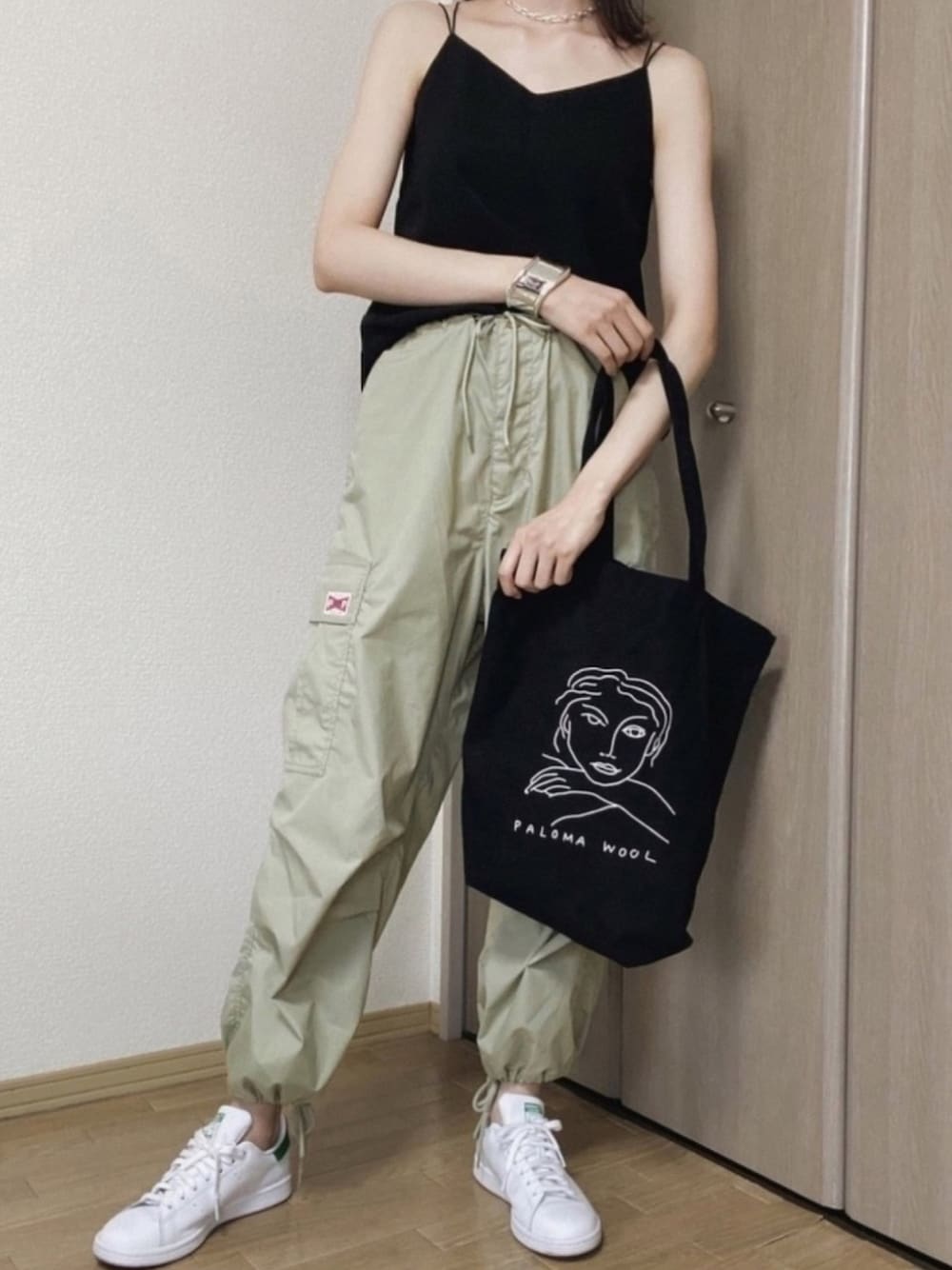 ブラック系のトートバッグ、グリーン系のカーゴパンツ、ホワイト系のスニーカーを着用したレディースの夏コーディネートの1枚目の写真
