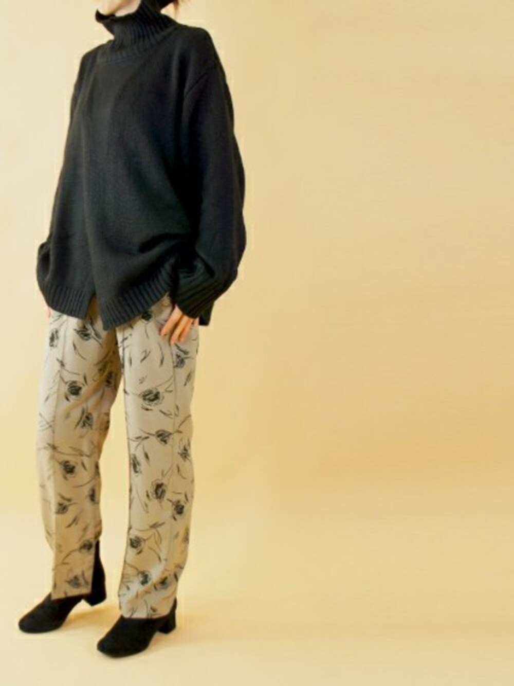 ブラック系のニット/セーター、ベージュ系のスラックスを着用したレディースの冬コーディネートの1枚目の写真