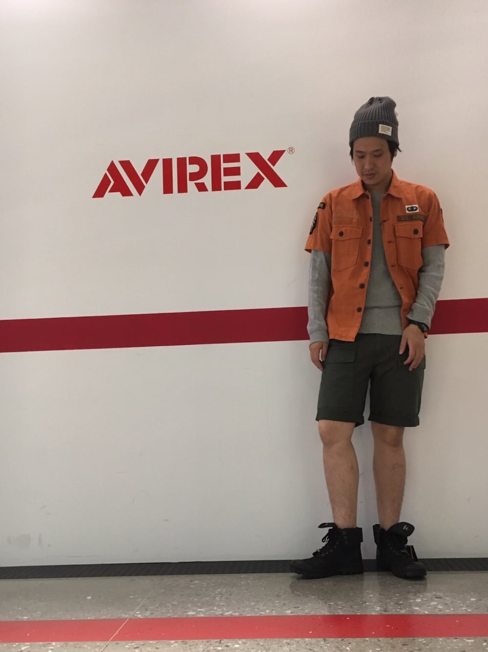 オレンジ系のシャツ/ブラウス、グリーン系のカーゴパンツ、ブラック系のブーツを着用したメンズの夏コーディネートの1枚目の写真