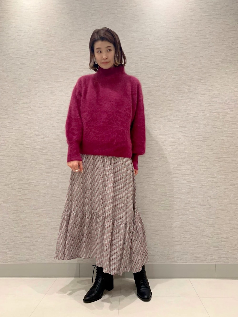 レッド系のニット/セーター、ピンク系のワンピース、ブラック系のブーツを着用したレディースの秋コーディネートの1枚目の写真