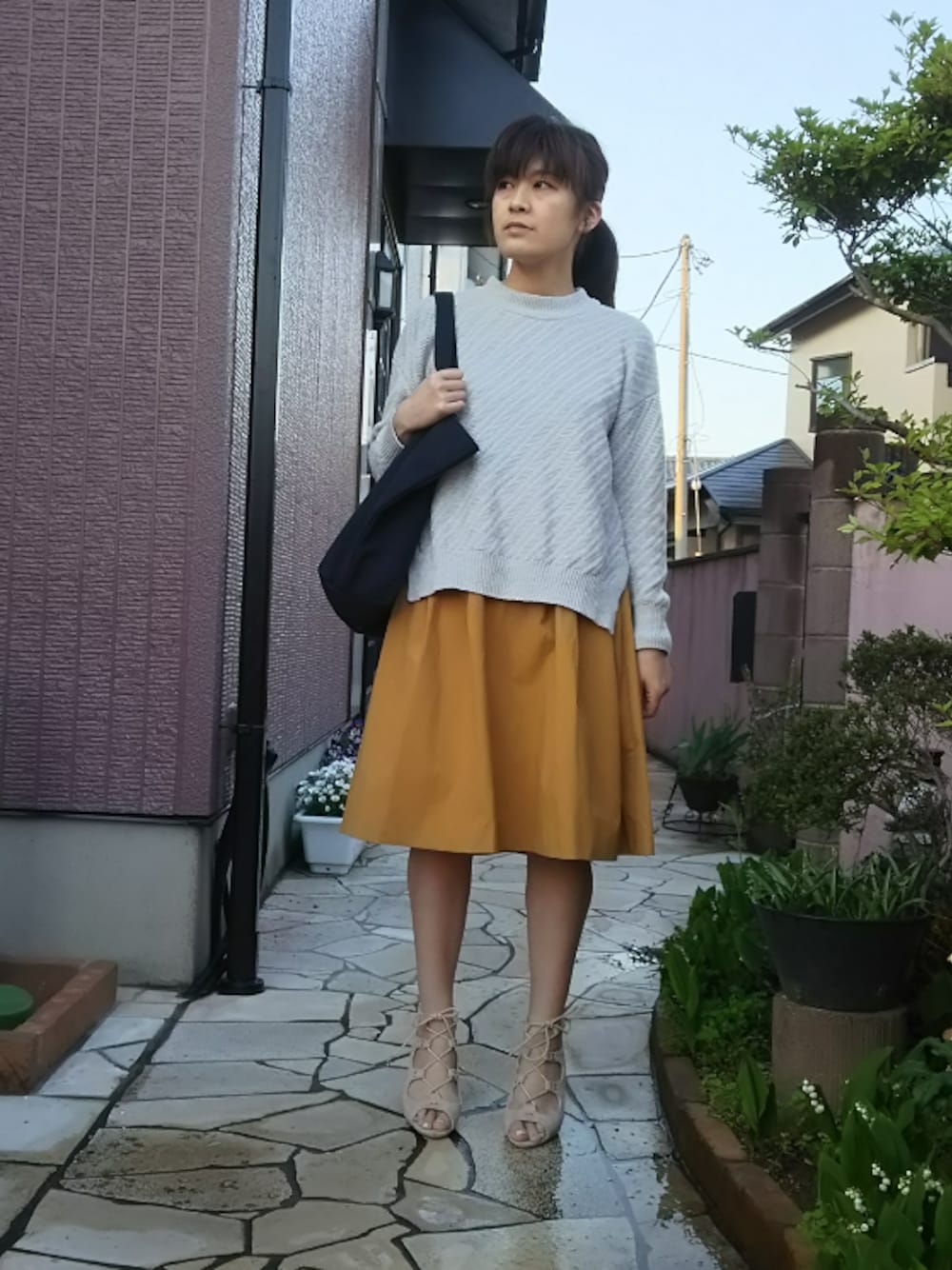 グレー系のニット/セーター、イエロー系のスカート、ブルー系のトートバッグを着用したレディースの春コーディネートの1枚目の写真