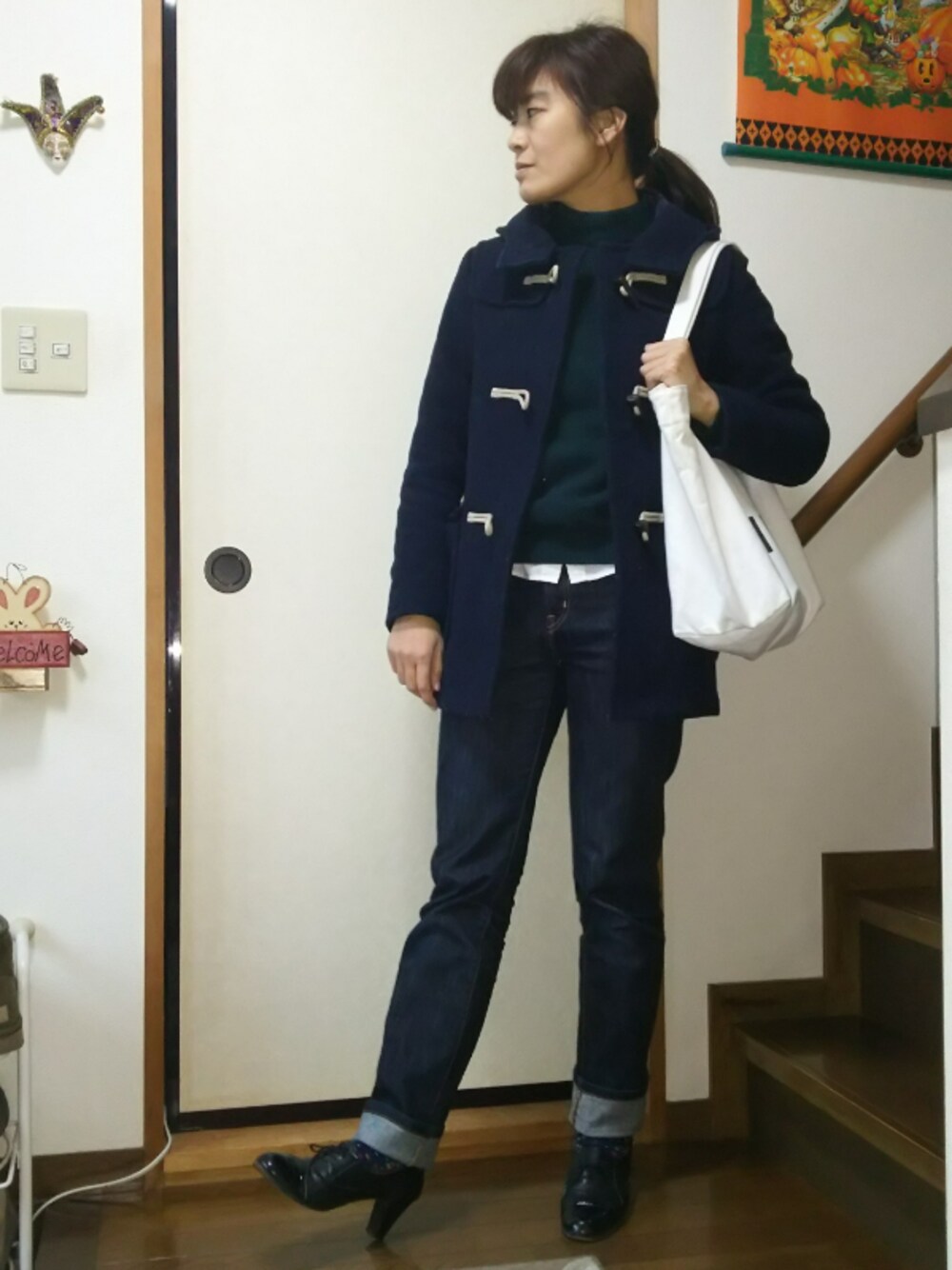 ブルー系のデニムパンツ、ホワイト系のトートバッグ、グリーン系のニット/セーターを着用したレディースの冬コーディネートの1枚目の写真