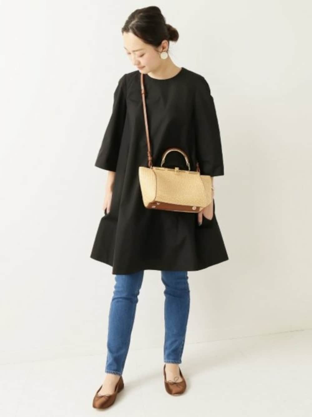 ブルー系のデニムパンツ、ブラック系のワンピース、ブラウン系のバレエシューズを着用したレディースの冬コーディネートの1枚目の写真