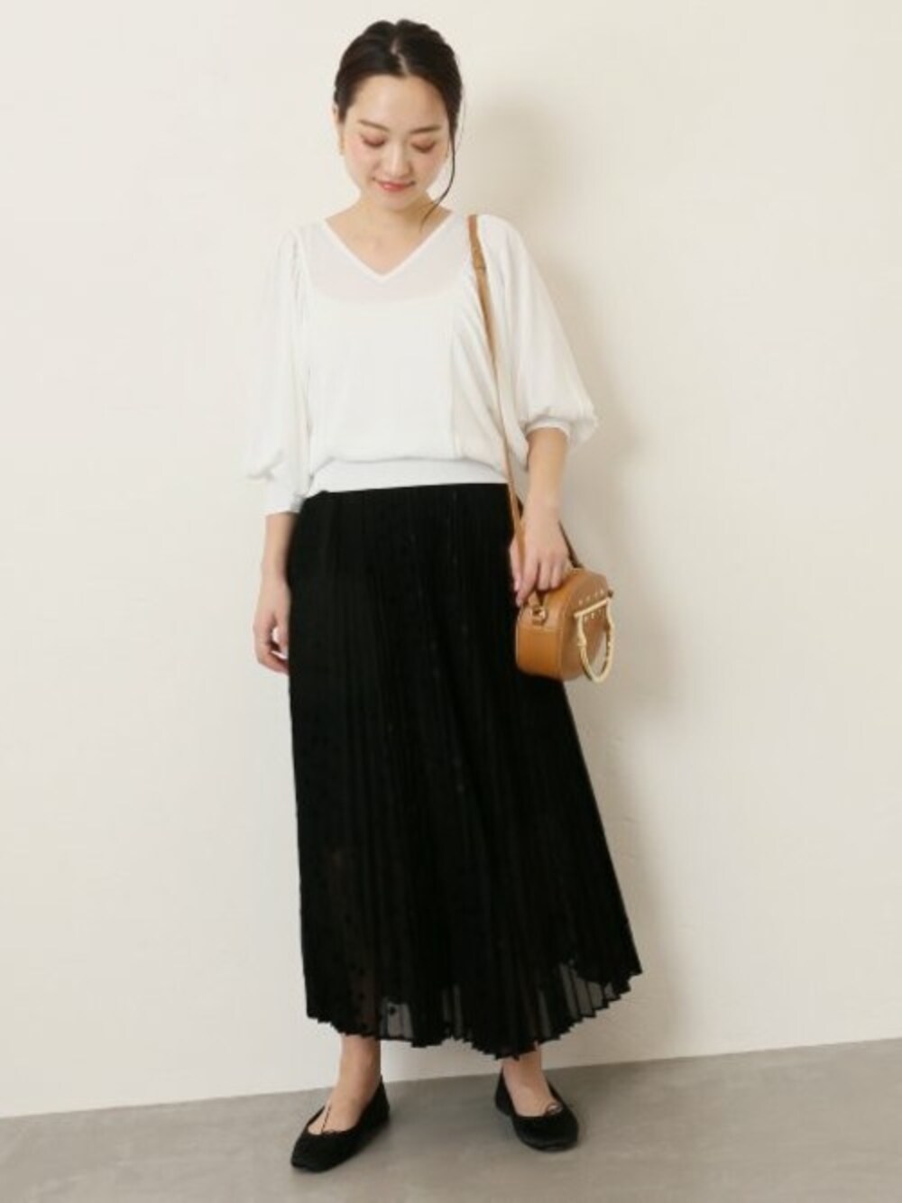 ホワイト系のニット/セーター、ブラック系のスカート、イエロー系のショルダーバッグを着用したレディースの春コーディネートの1枚目の写真