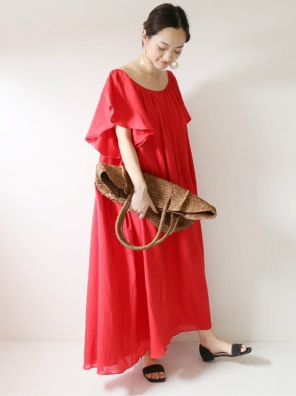 レッド系のワンピース、ブラウン系のかごバッグ、グレー系のサンダルを着用したレディースの夏コーディネートの1枚目の写真