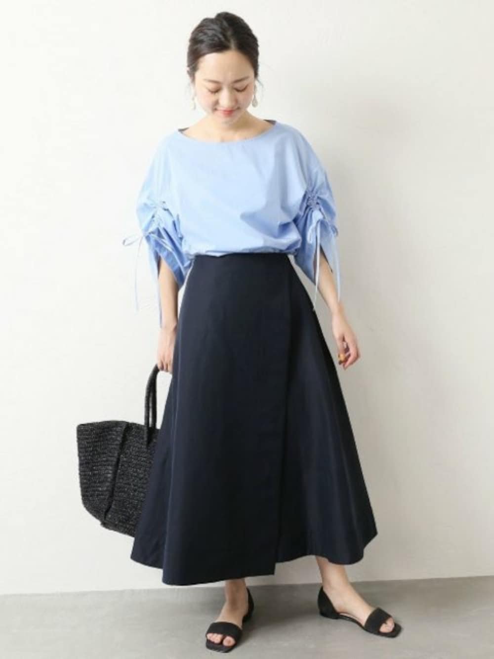 ブルー系のシャツ/ブラウス、ブルー系のスカート、ブラック系のかごバッグを着用したレディースの夏コーディネートの1枚目の写真