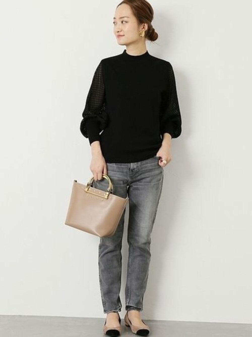 シルバー系のデニムパンツ、ブラック系のニット/セーター、ベージュ系のショルダーバッグを着用したレディースの秋コーディネートの1枚目の写真