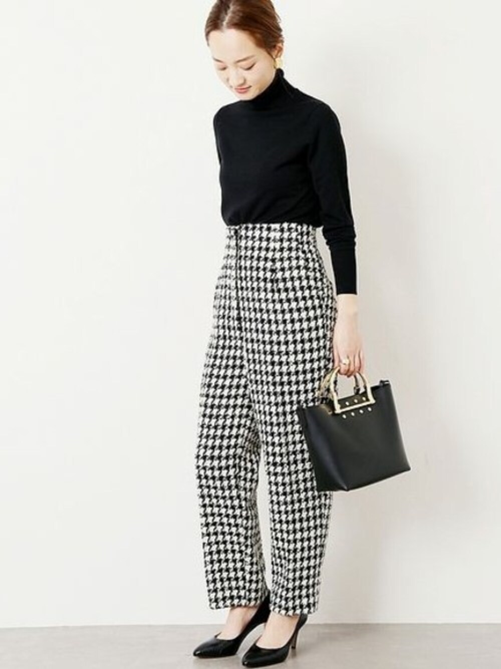 ブラック系のニット/セーター、ブラック系のショルダーバッグ、ブラック系のパンプスを着用したレディースの冬コーディネートの1枚目の写真