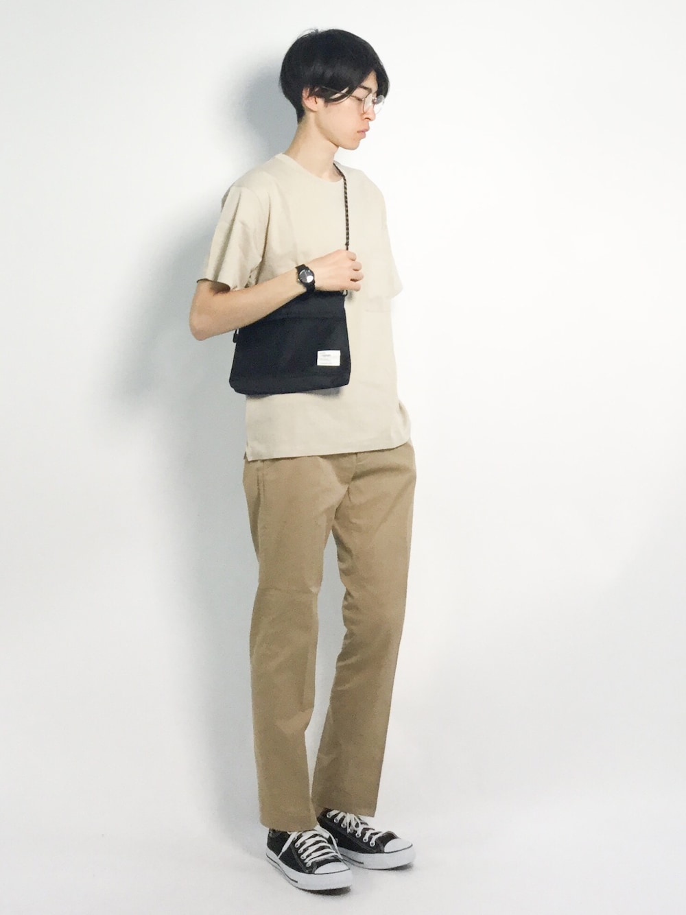 ホワイト系のTシャツ/カットソー、ベージュ系のチノパンツ、ブラック系のショルダーバッグを着用したメンズの夏コーディネートの1枚目の写真