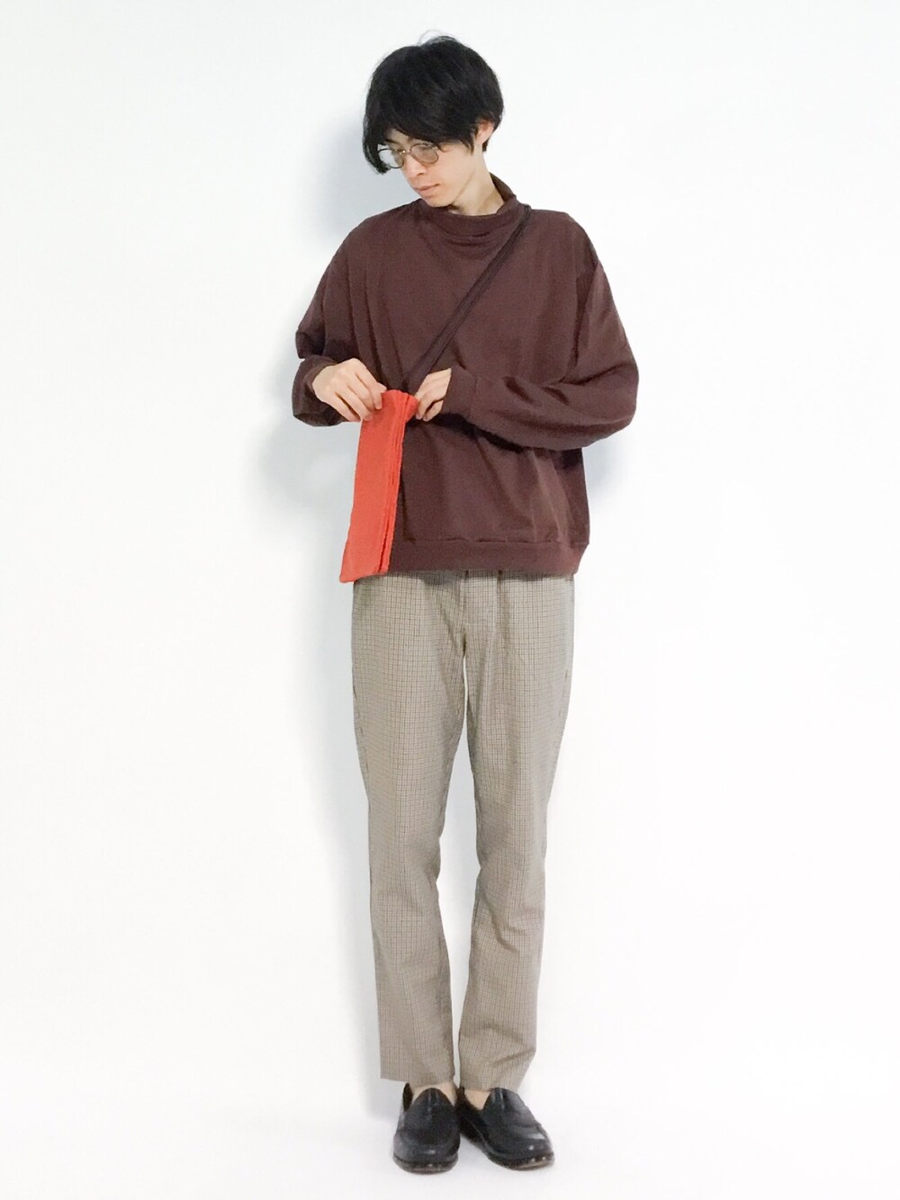 レッド系のショルダーバッグ、レッド系のTシャツ/カットソー、ベージュ系のスラックスを着用したメンズの秋コーディネートの1枚目の写真