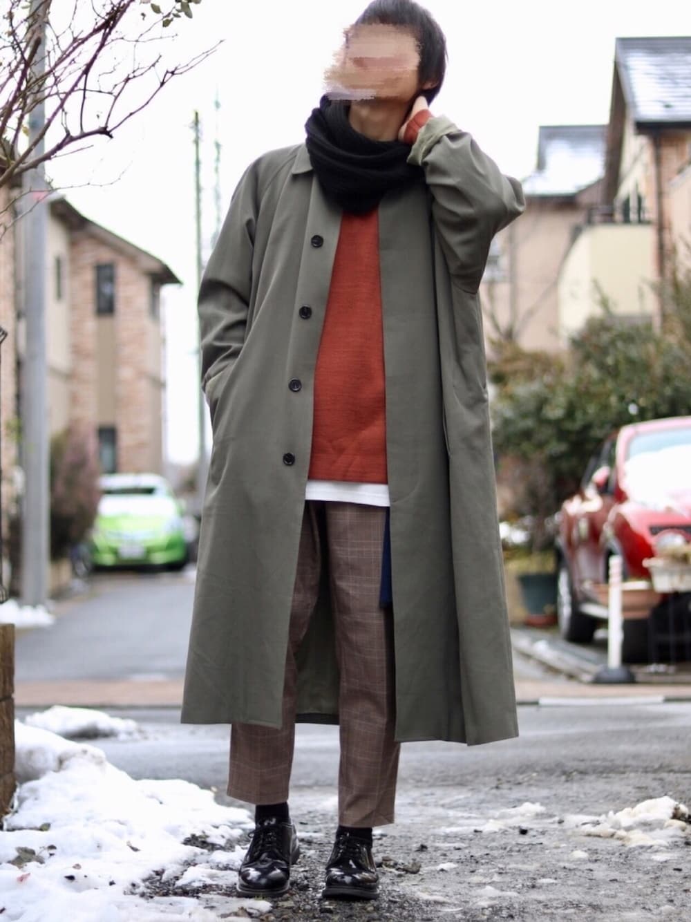 グリーン系のステンカラーコート、ブラウン系のニット/セーター、ホワイト系のTシャツ/カットソーを着用したメンズの冬コーディネートの1枚目の写真