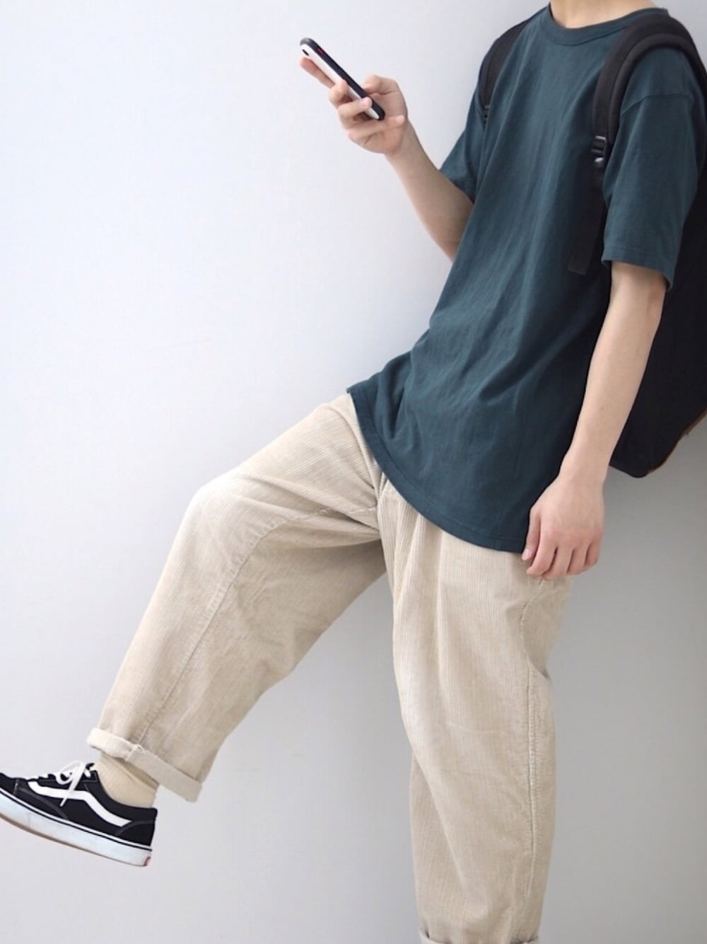 グリーン系のTシャツ/カットソー、ベージュ系のパンツ、ブラック系のスニーカーを着用したメンズの春コーディネートの1枚目の写真