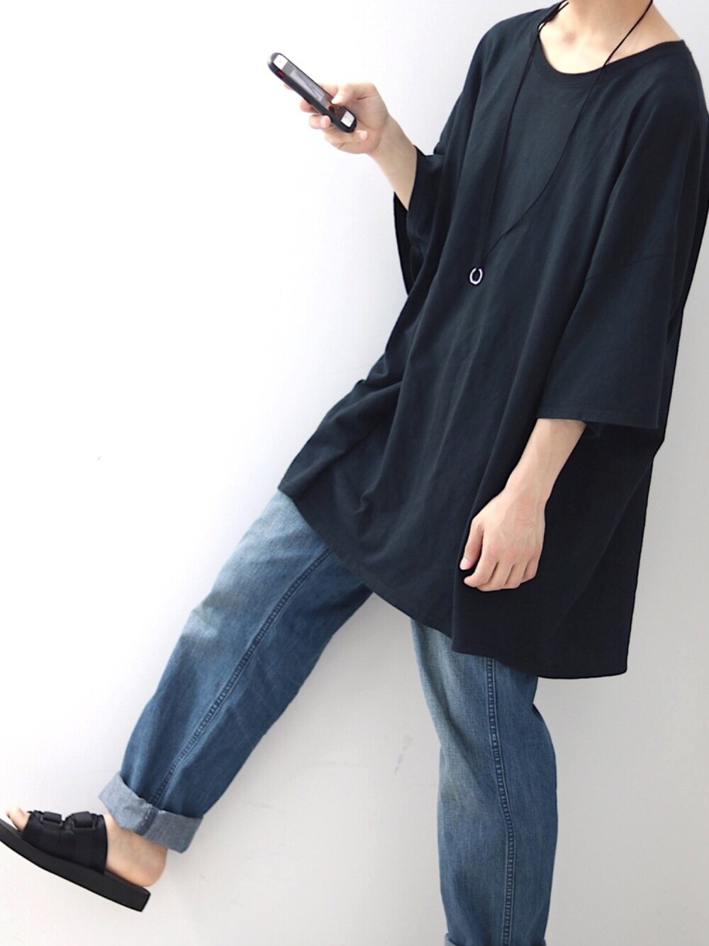 ブラック系のTシャツ/カットソー、ブルー系のデニムパンツ、ブラック系のサンダルを着用したメンズの春コーディネートの1枚目の写真