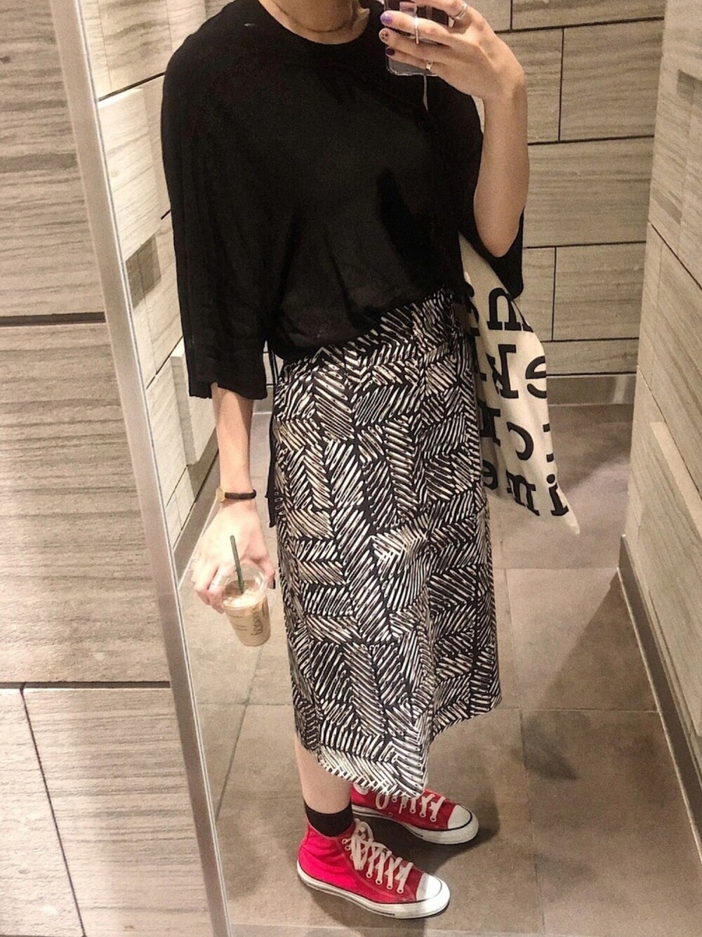 レッド系のスニーカー、ブラック系のスカートを着用したレディースの秋コーディネートの1枚目の写真