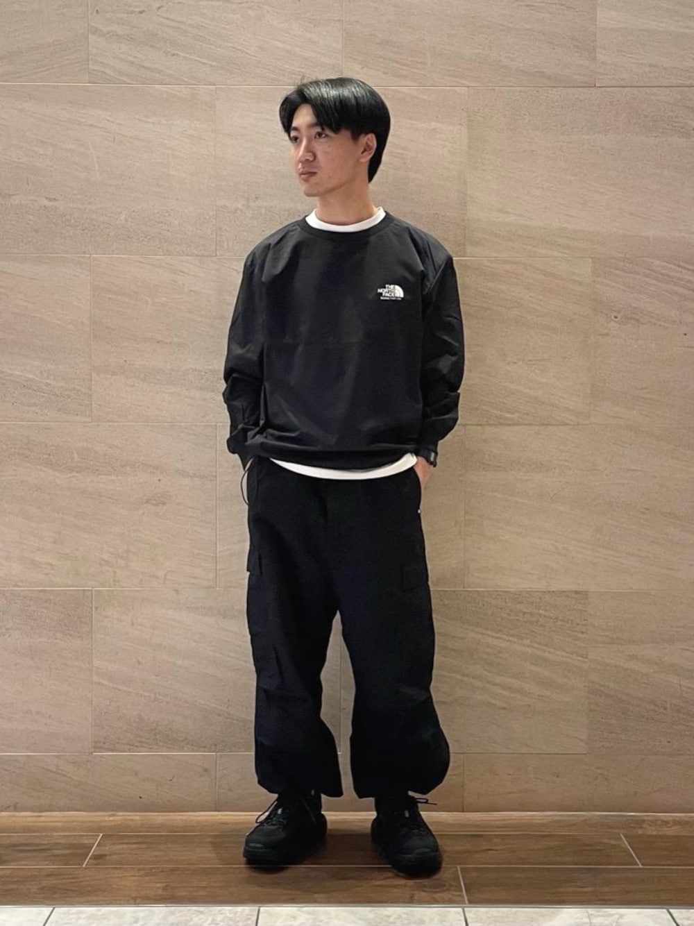 ブラック系のスニーカー、ブラック系のカーゴパンツ、ブラック系のTシャツ/カットソーを着用したメンズの冬コーディネートの1枚目の写真