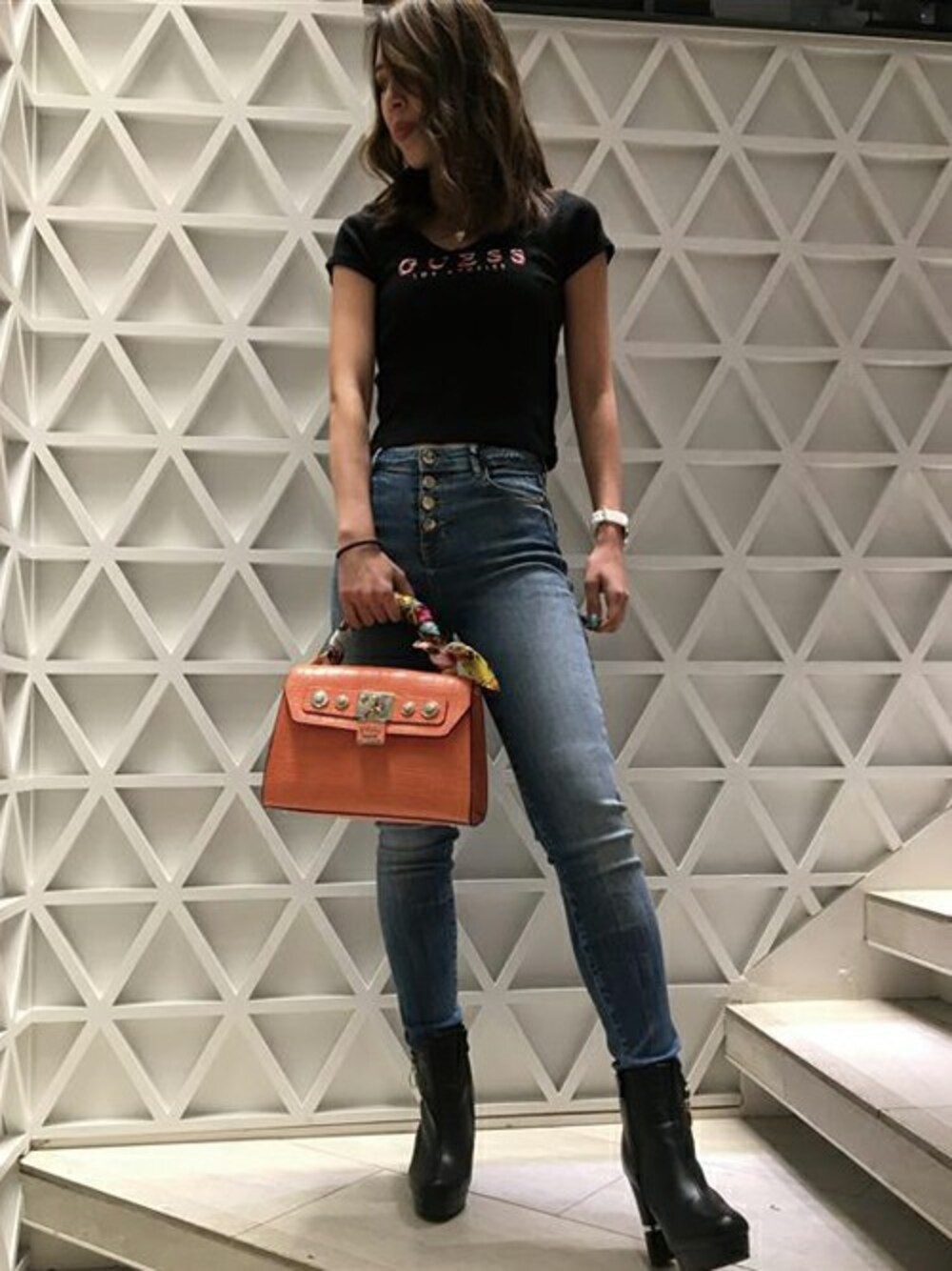 ブルー系のデニムパンツ、ブラック系のTシャツ/カットソー、オレンジ系のショルダーバッグを着用したレディースの冬コーディネートの1枚目の写真