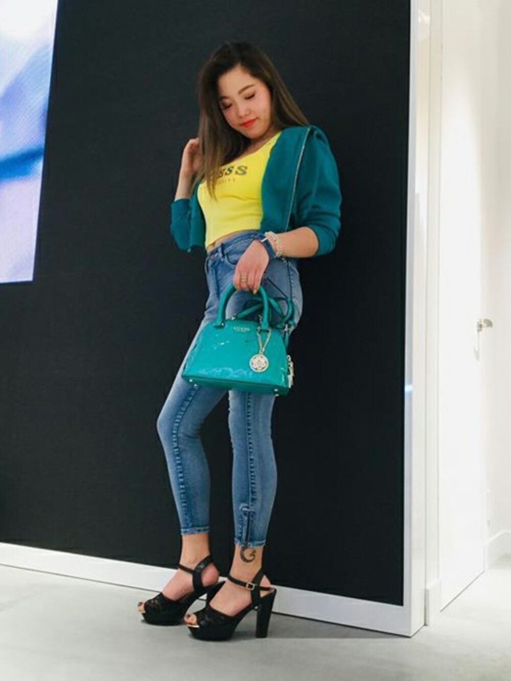 グリーン系のパーカー、イエロー系のタンクトップ、ブラック系のデニムパンツを着用したレディースの春コーディネートの1枚目の写真