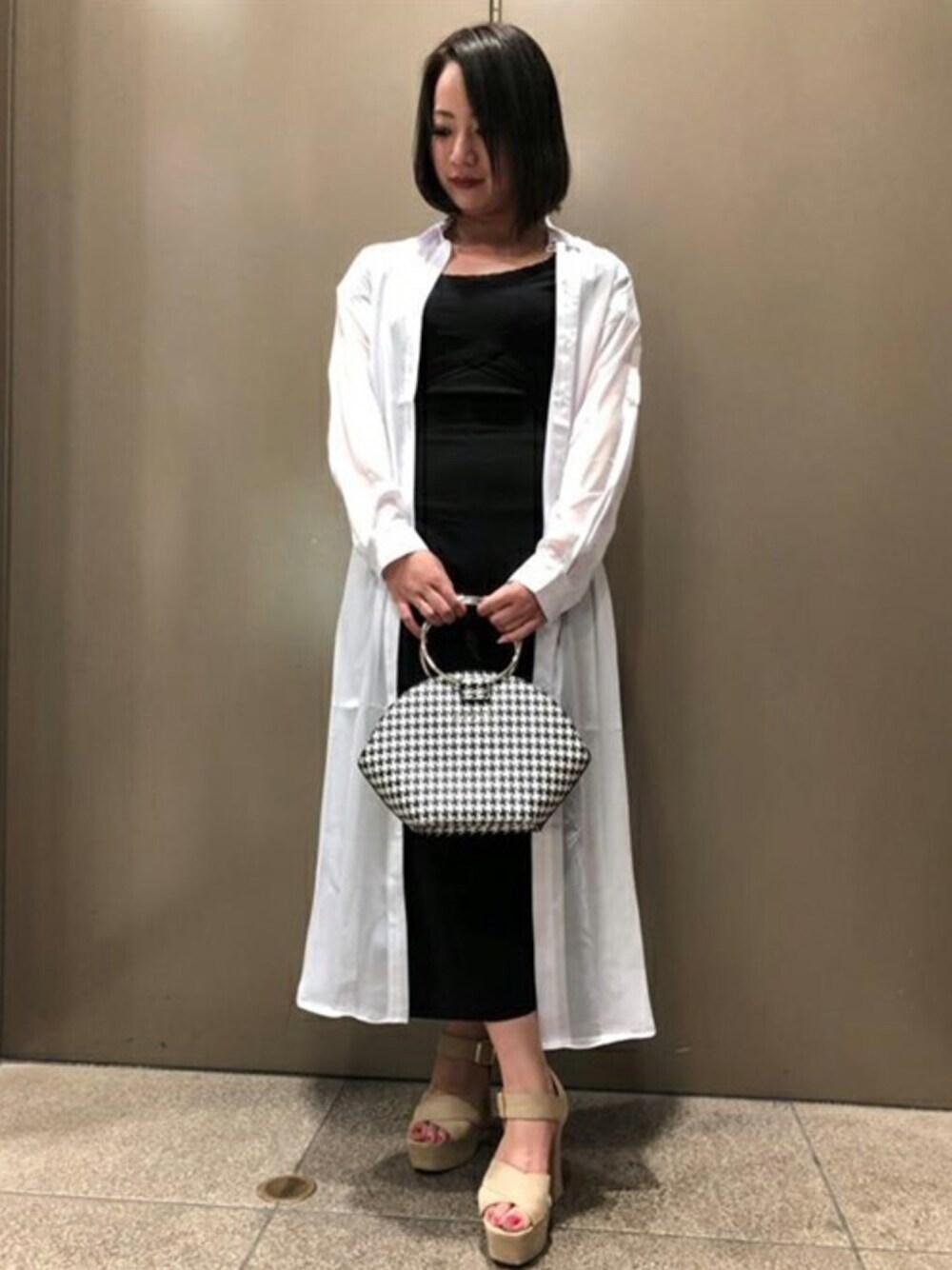 ブラック系のつなぎ/オールインワン、ホワイト系のシャツ/ブラウス、ブラック系のハンドバッグを着用したレディースの春コーディネートの1枚目の写真