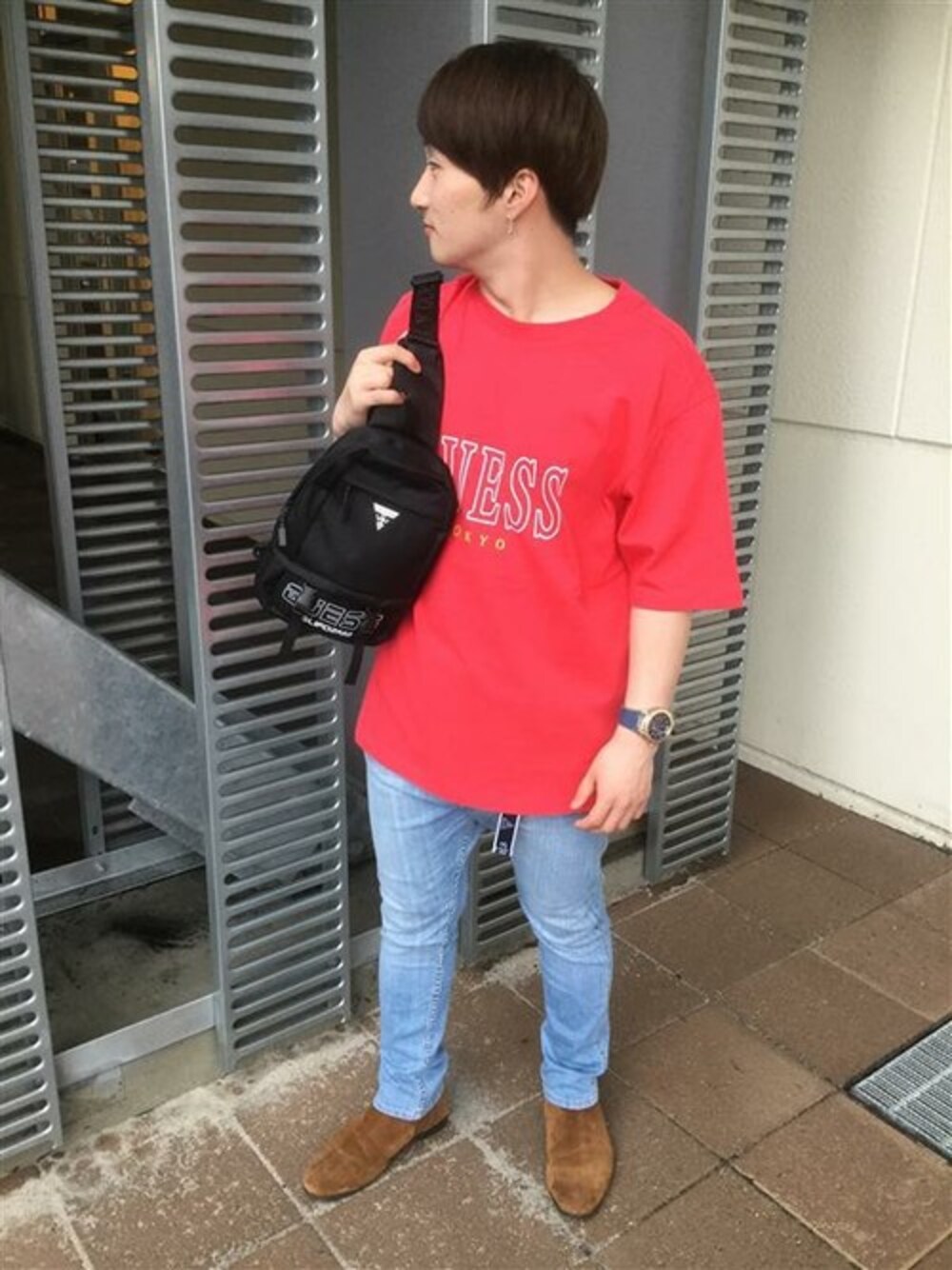 レッド系のTシャツ/カットソー、ブルー系のデニムパンツ、ブラック系のバックパック/リュックを着用したメンズの夏コーディネートの1枚目の写真