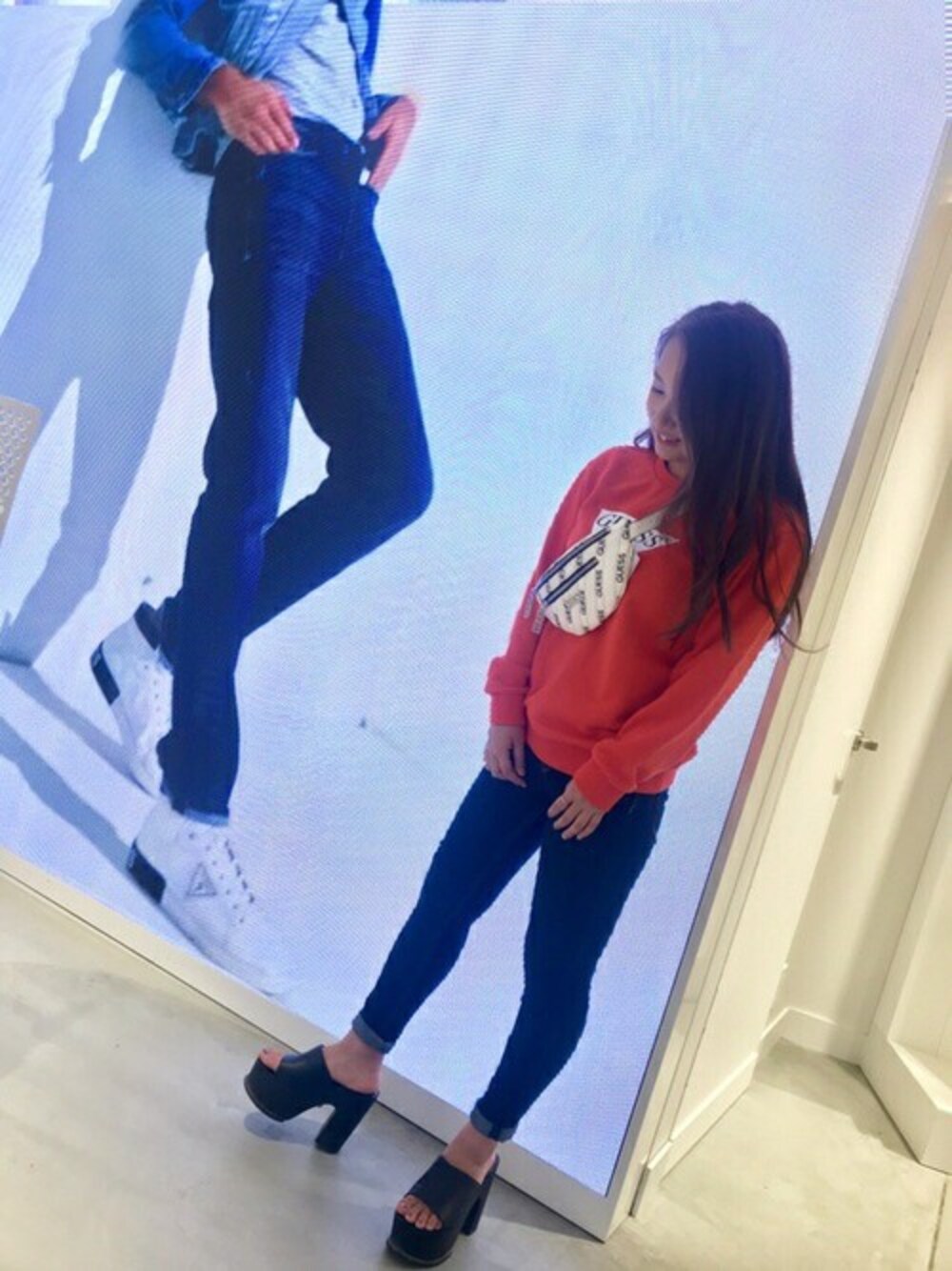 ホワイト系のスウェット、ブルー系のデニムパンツ、ホワイト系のボディバッグ/ウエストポーチを着用したレディースの秋コーディネートの1枚目の写真