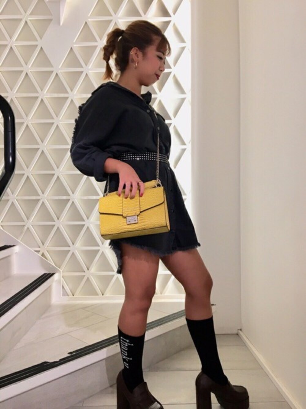 ブラック系のシャツワンピース、イエロー系のハンドバッグを着用したレディースの秋コーディネートの1枚目の写真