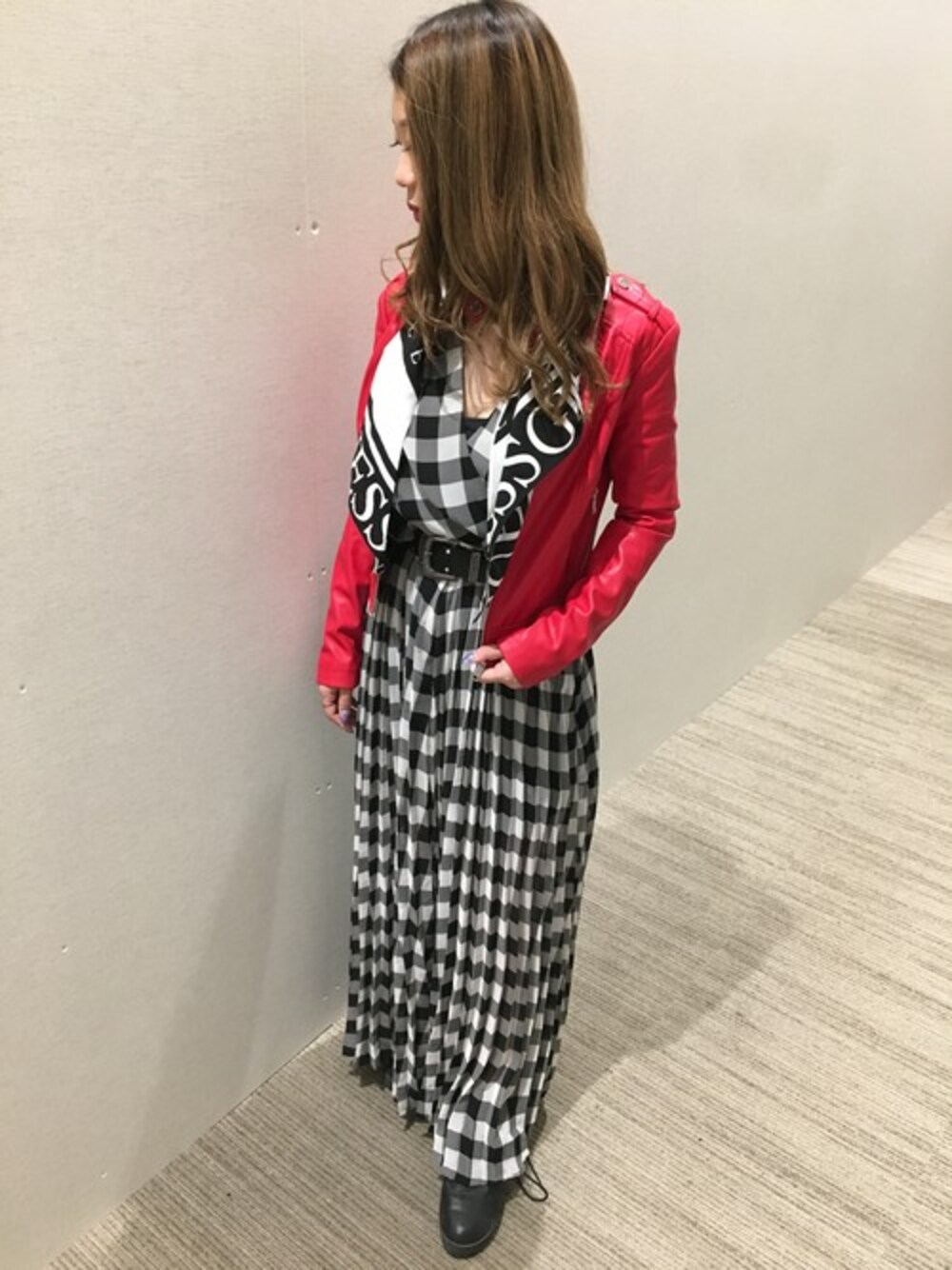 レッド系のライダースジャケット、ブラック系のワンピースを着用したレディースの秋コーディネートの1枚目の写真