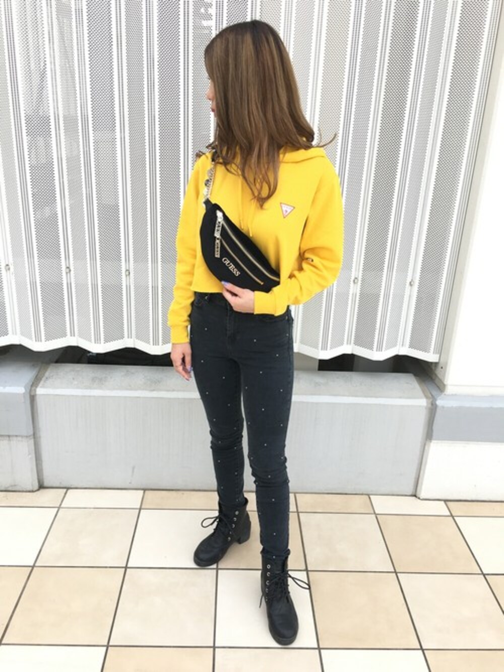 イエロー系のパーカー、ブルー系のデニムパンツ、ブラック系のボディバッグ/ウエストポーチを着用したレディースの秋コーディネートの1枚目の写真