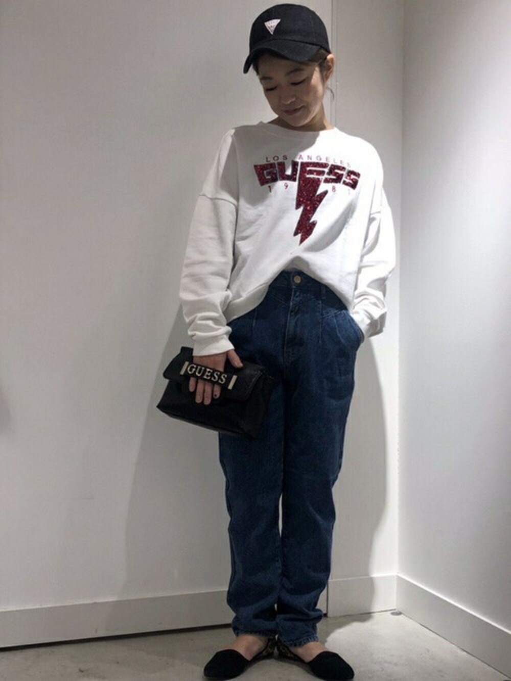 ブルー系のデニムパンツ、ブラック系のショルダーバッグ、ホワイト系のスウェットを着用したレディースの秋コーディネートの1枚目の写真