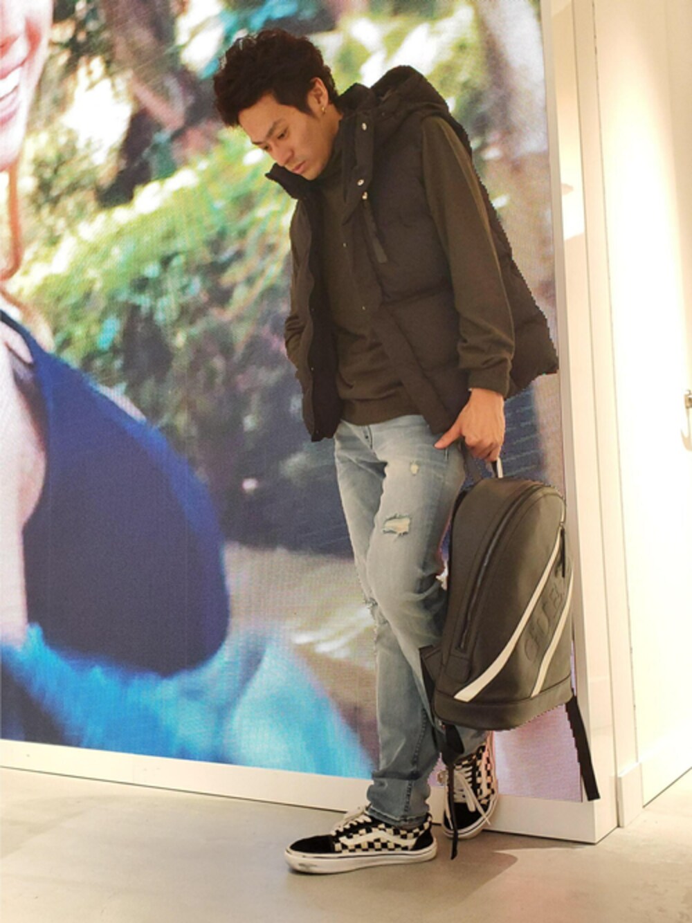 グリーン系のニット/セーター、ブルー系のデニムパンツ、ブラック系のバックパック/リュックを着用したレディースの秋コーディネートの1枚目の写真