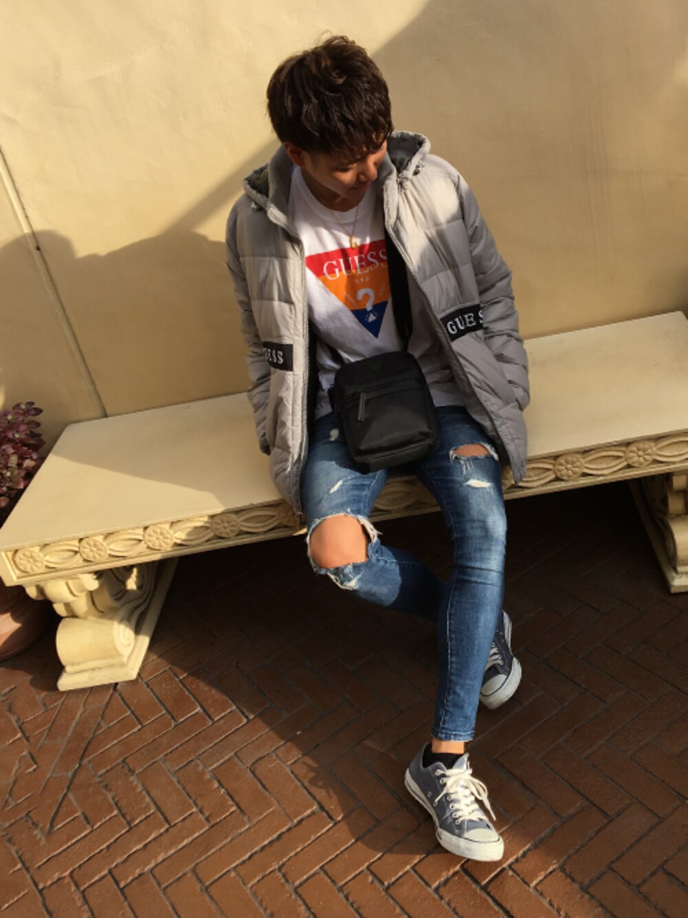 ブラック系のショルダーバッグ、ブルー系のデニムパンツ、ホワイト系のTシャツ/カットソーを着用したメンズの秋コーディネートの1枚目の写真