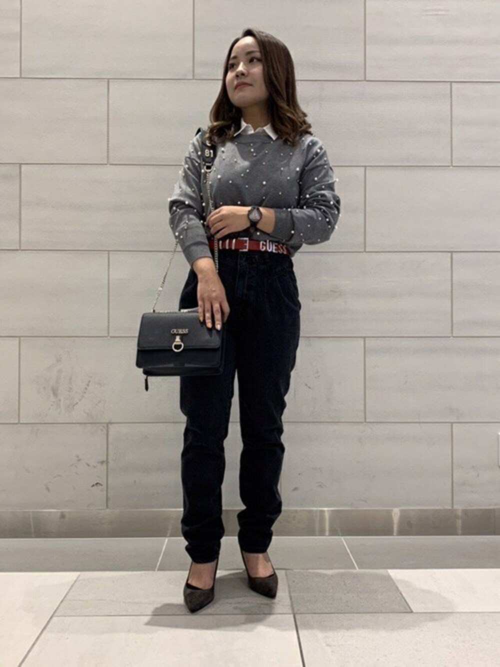 グレー系のニット/セーター、ホワイト系のシャツ/ブラウス、グレー系のデニムパンツを着用したレディースの秋コーディネートの1枚目の写真