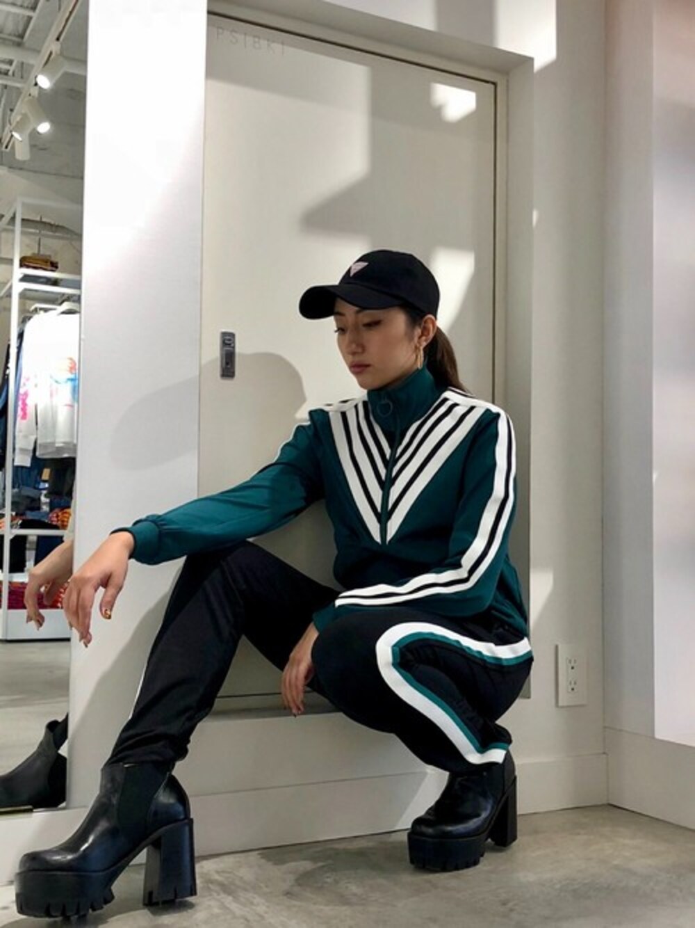 グリーン系のジャージ、ブラック系のその他パンツ、ブラック系のキャップを着用したレディースの秋コーディネートの1枚目の写真