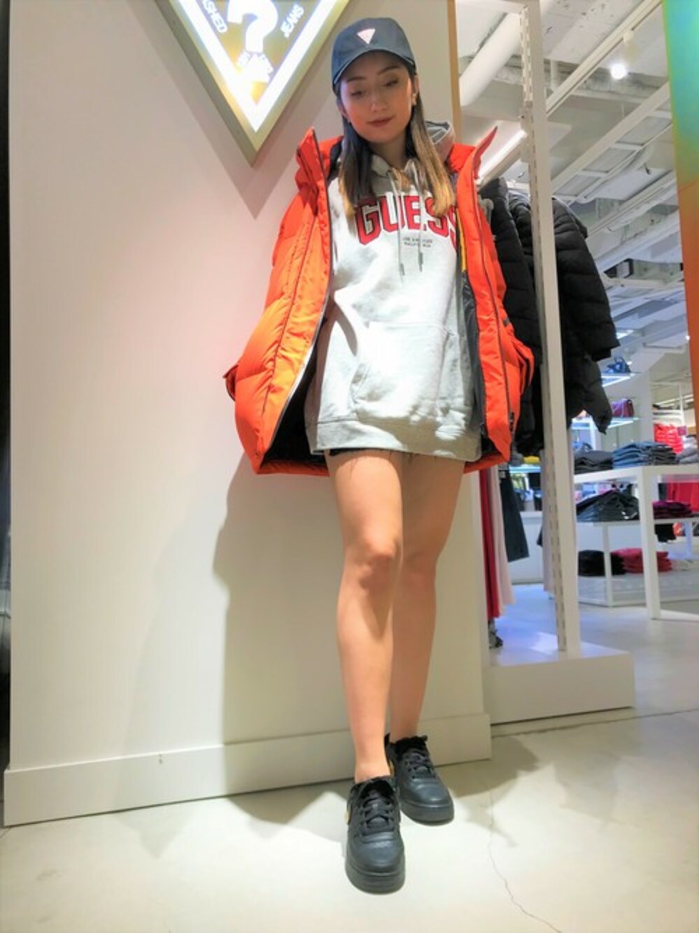 グレー系のスウェット、オレンジ系のダウンジャケット/コート、ブラック系のキャップを着用したレディースの冬コーディネートの1枚目の写真