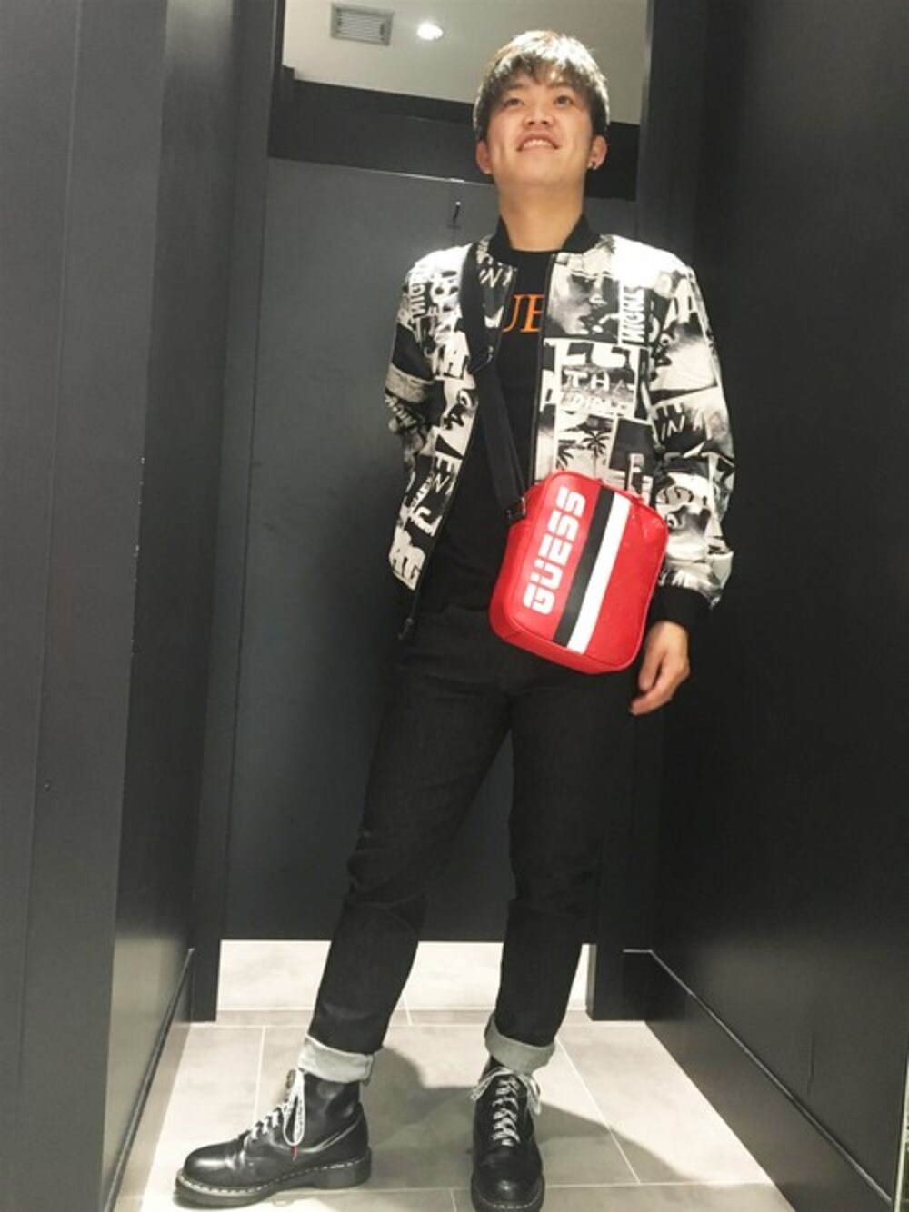 「ブルゾン、ジャケット、アウター、ロゴT、スキニー、ショルダーバッグ、Tシャツ、総柄、黒スキニー、guess」｜「GuessのLOGO-FILL GRAPHIC TEE（Tシャツ/カットソー、ブラック系）」を使った、GUESS JAPANさん（メンズ・173cm）の冬コーディネートの1枚目の写真