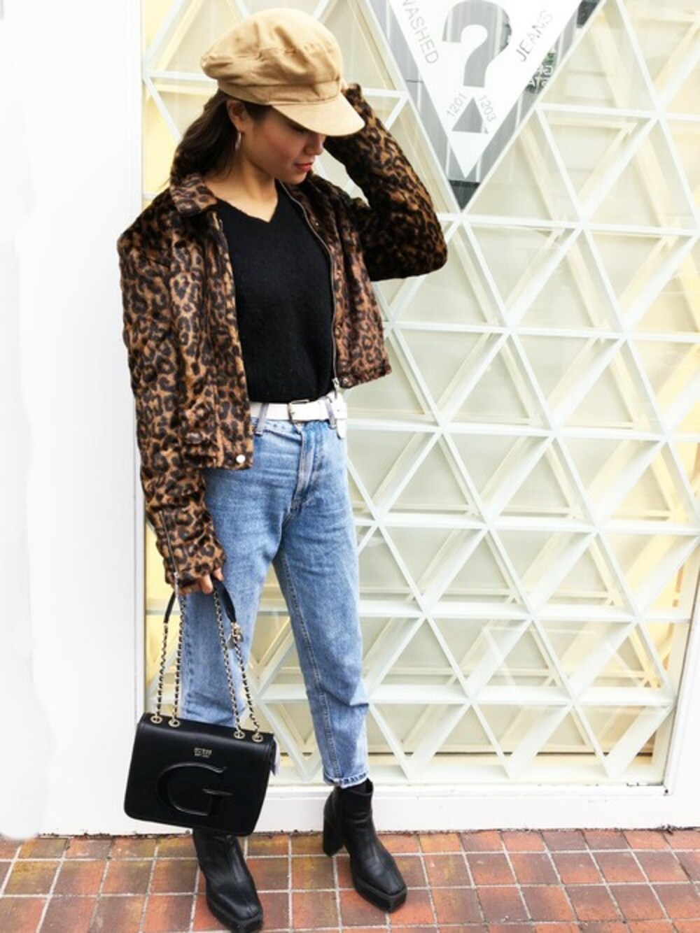 ブラック系のショルダーバッグ、ブラック系のニット/セーター、ブルー系のデニムパンツを着用したレディースの冬コーディネートの1枚目の写真