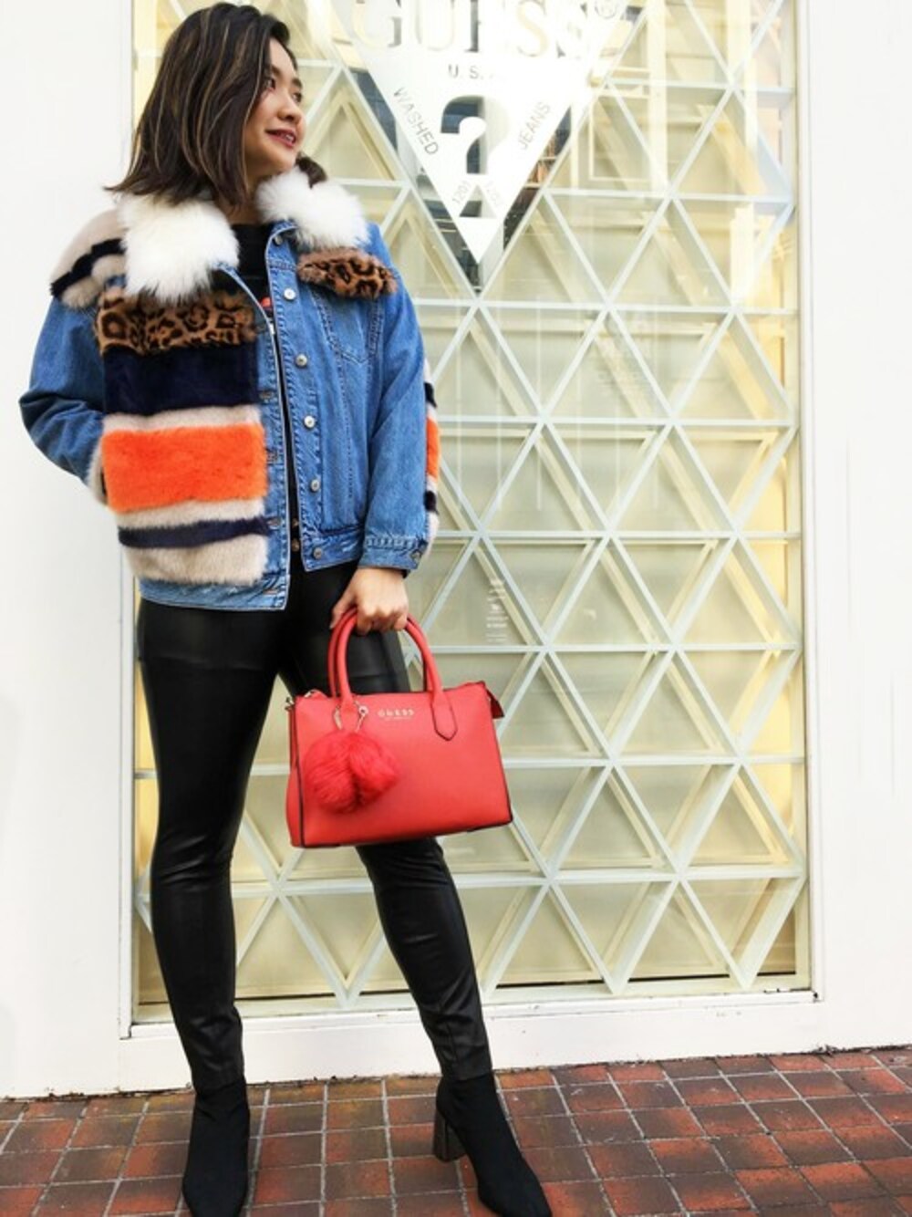ブルー系のデニムジャケット、レッド系のハンドバッグ、ブラック系のスウェットを着用したレディースの冬コーディネートの1枚目の写真